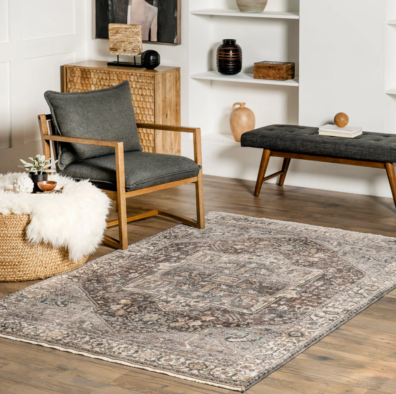 Vintage distressed medallion area rug in a modern living room with a grey armchair and wooden furniture.