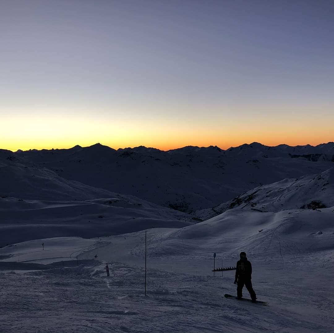 Skier overlooking snowy alpine slopes at sunset in Val Thorens with direct access to the 3 Valleys ski area
