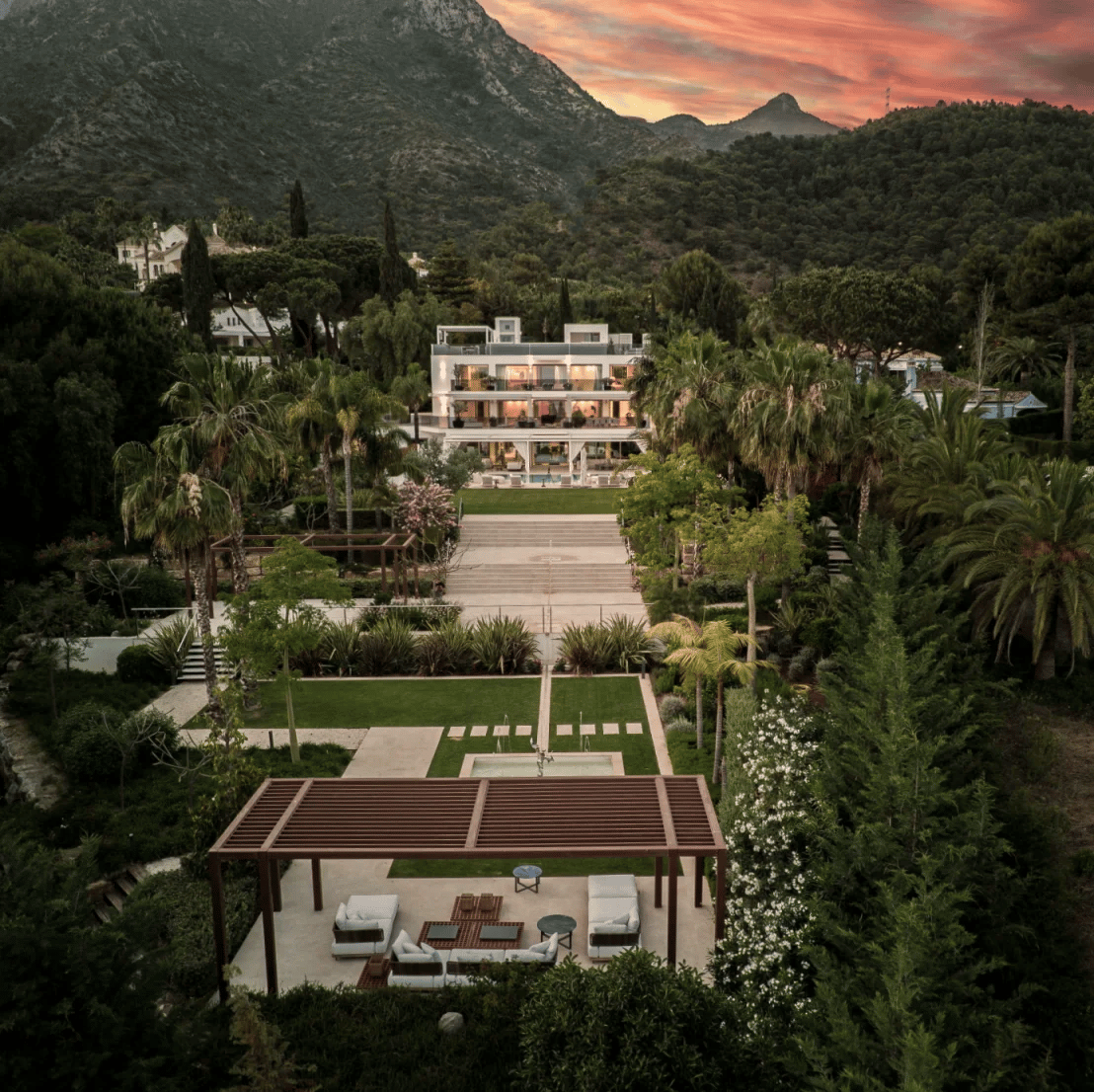 Aerial view of a modern white villa in a mountain valley at sunset