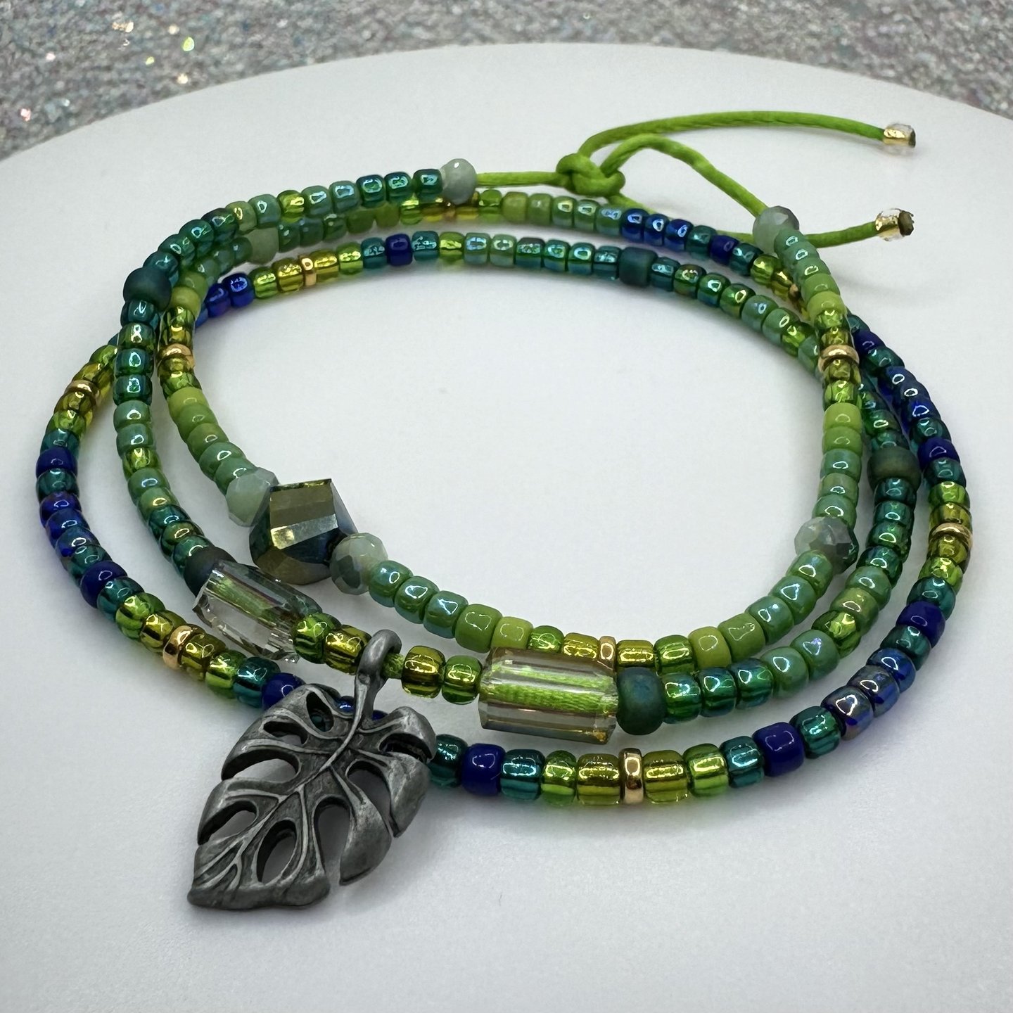 Tiny iridescent glass beads in vibrant shades of green blue & gold in a triple wrap bracelet design