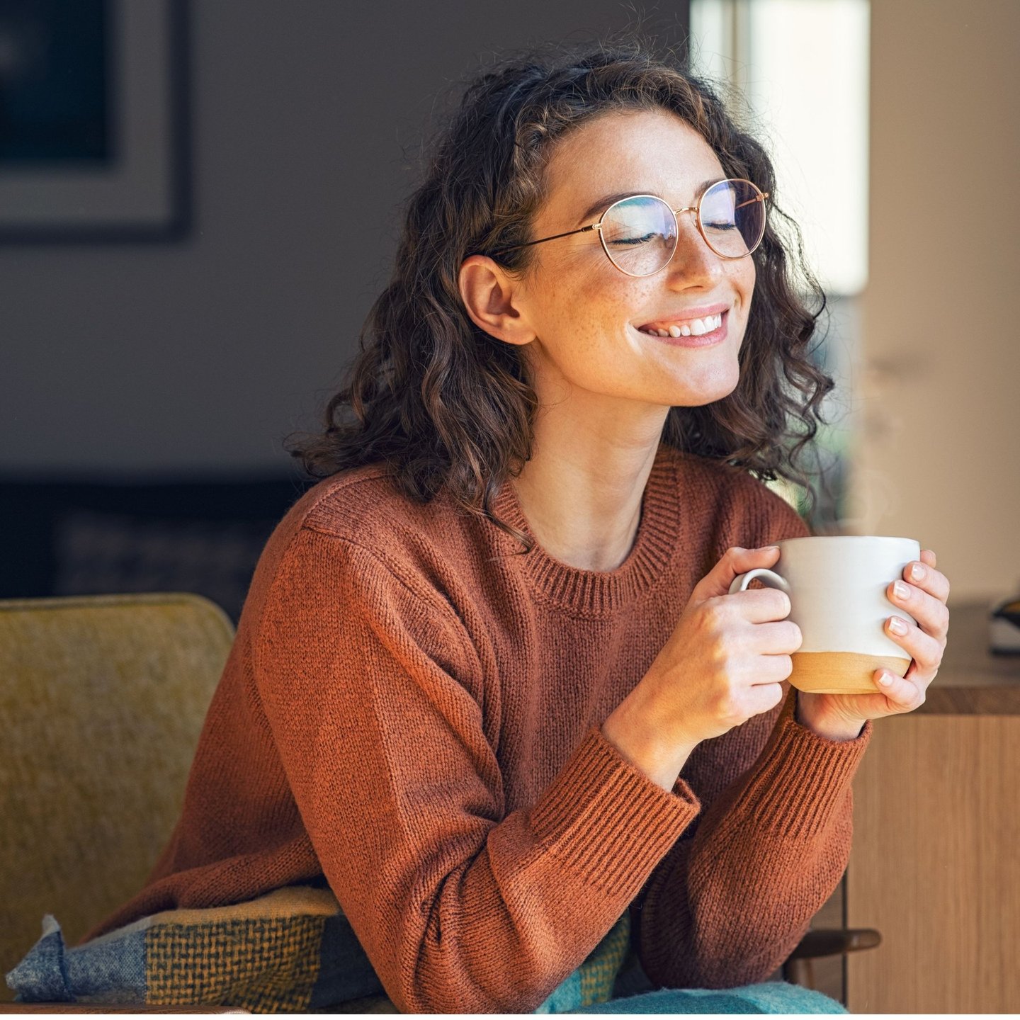 A person sitting comfortably near a window in Calgary with a cup of tea, relaxed posture