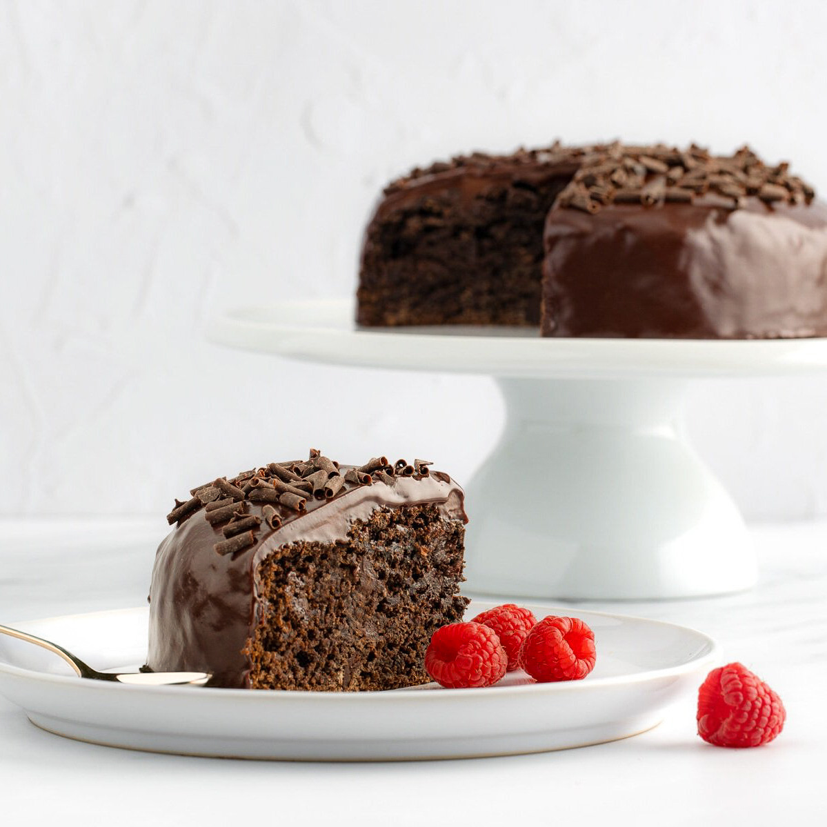 a slice of chocolate cake with chocolate frosting and raspberries