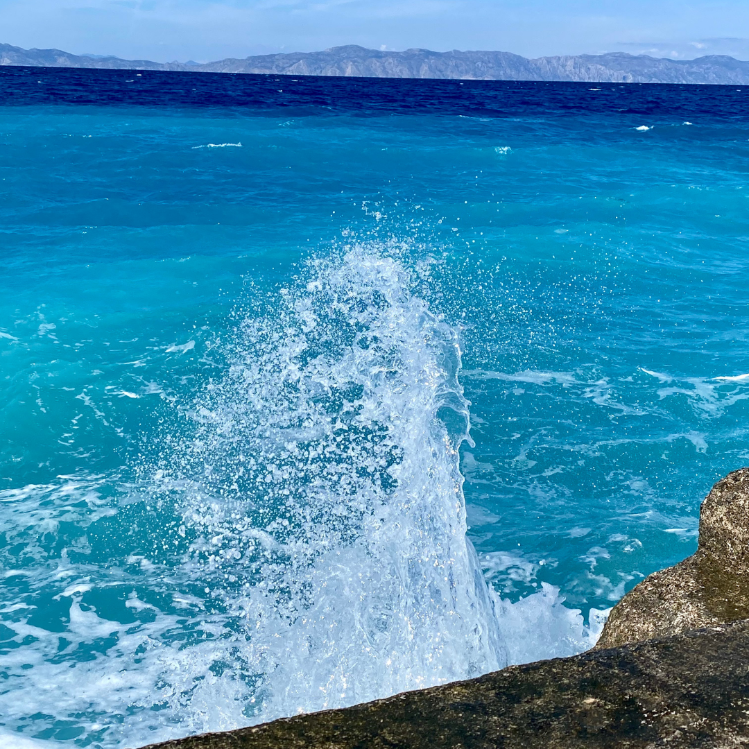 a wave crashing into the ocean on a sunny day