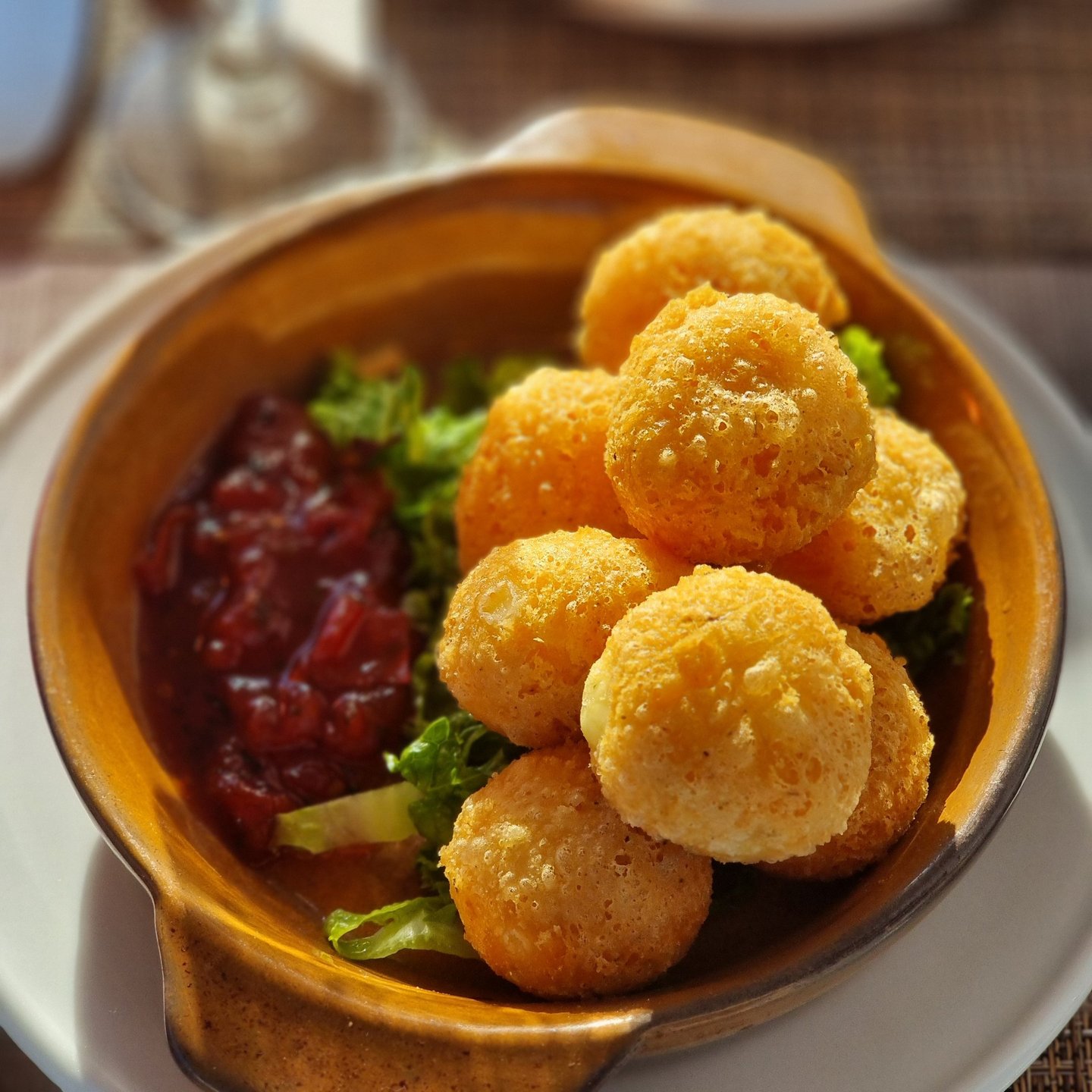 Golden fried breaded brie cheese balls served with a sweet cranberry dipping sauce and garnish.