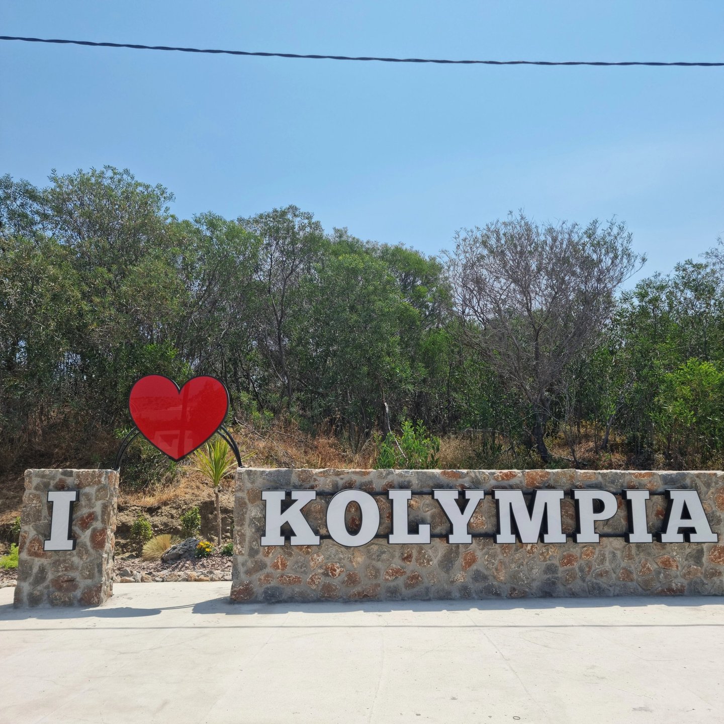 A stone monument reading I Love Kolympia with a red heart icon at the entrance to the Rhodes resort town.