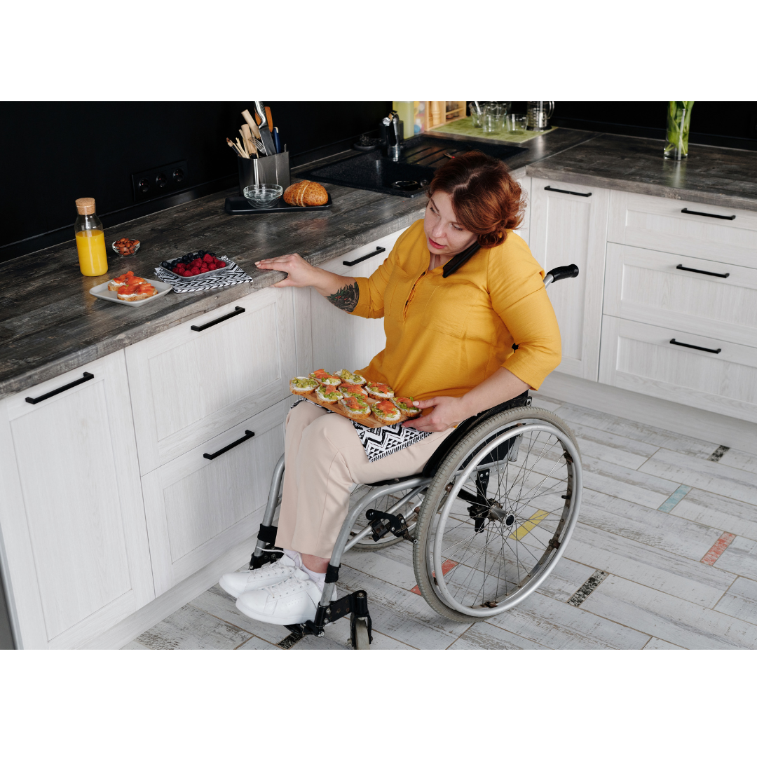 a woman in a wheelchair in her kitchen with a platter of food