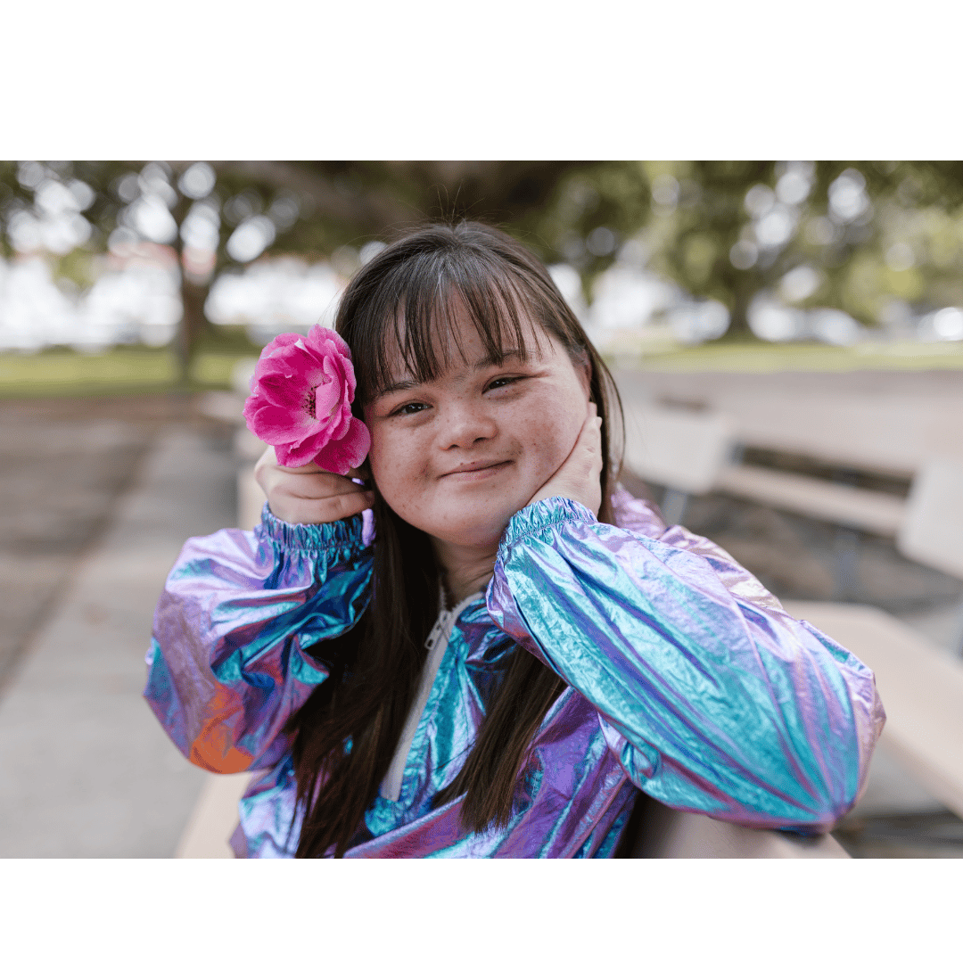 a beautiful young women with downs with a pink flower in her hair