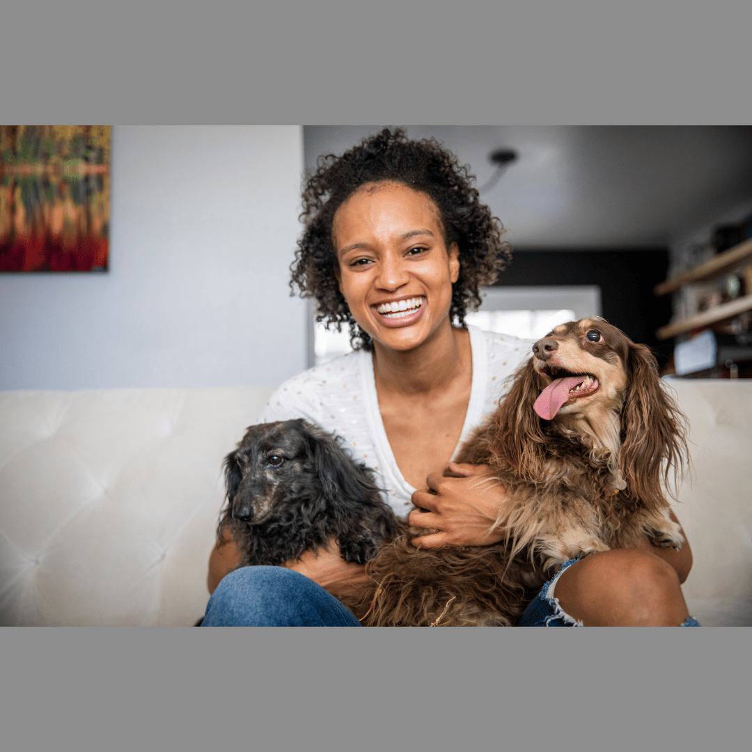 A beautiful young black woman holding her two elderly dogs