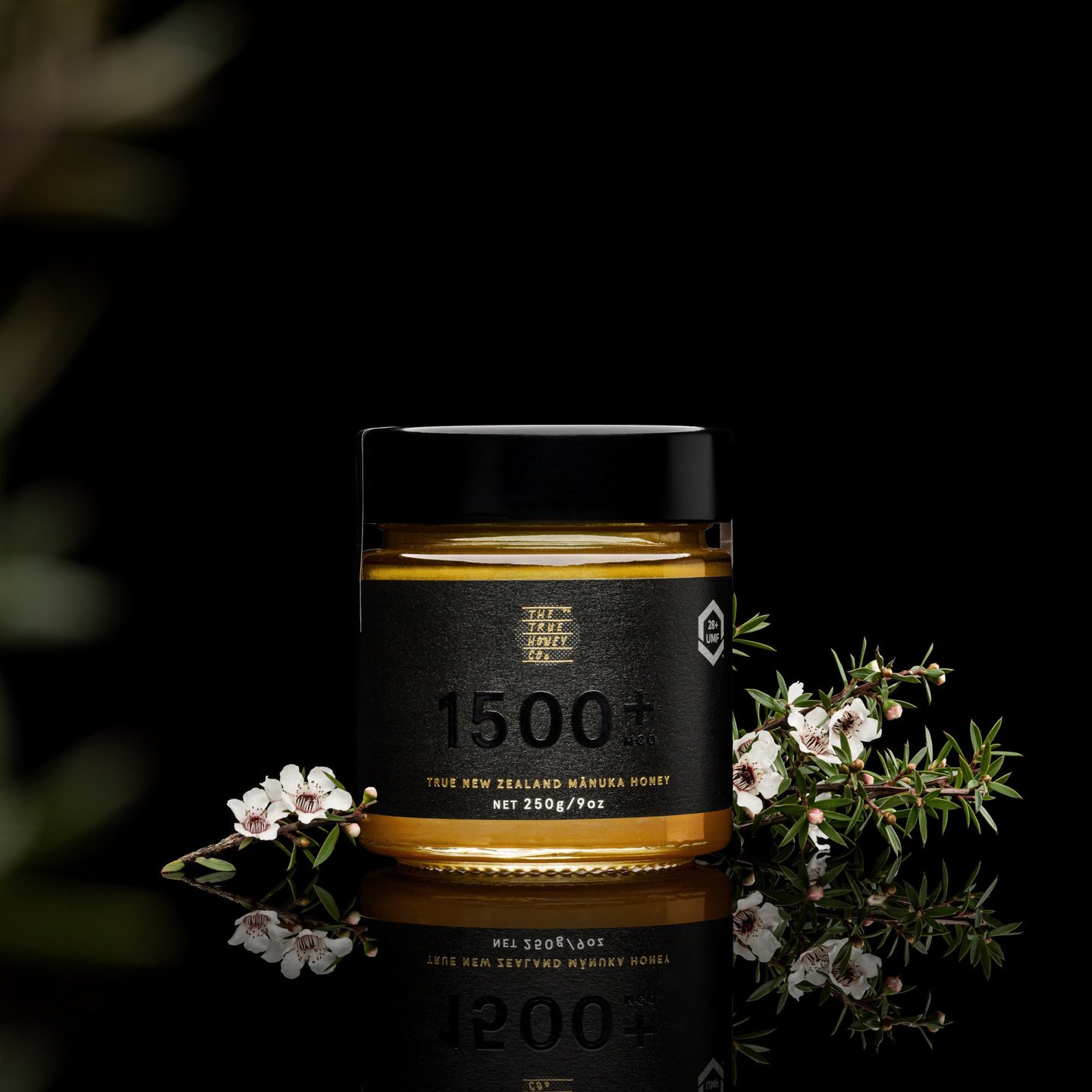 Product photography - a jar of honey with flowers and a black background