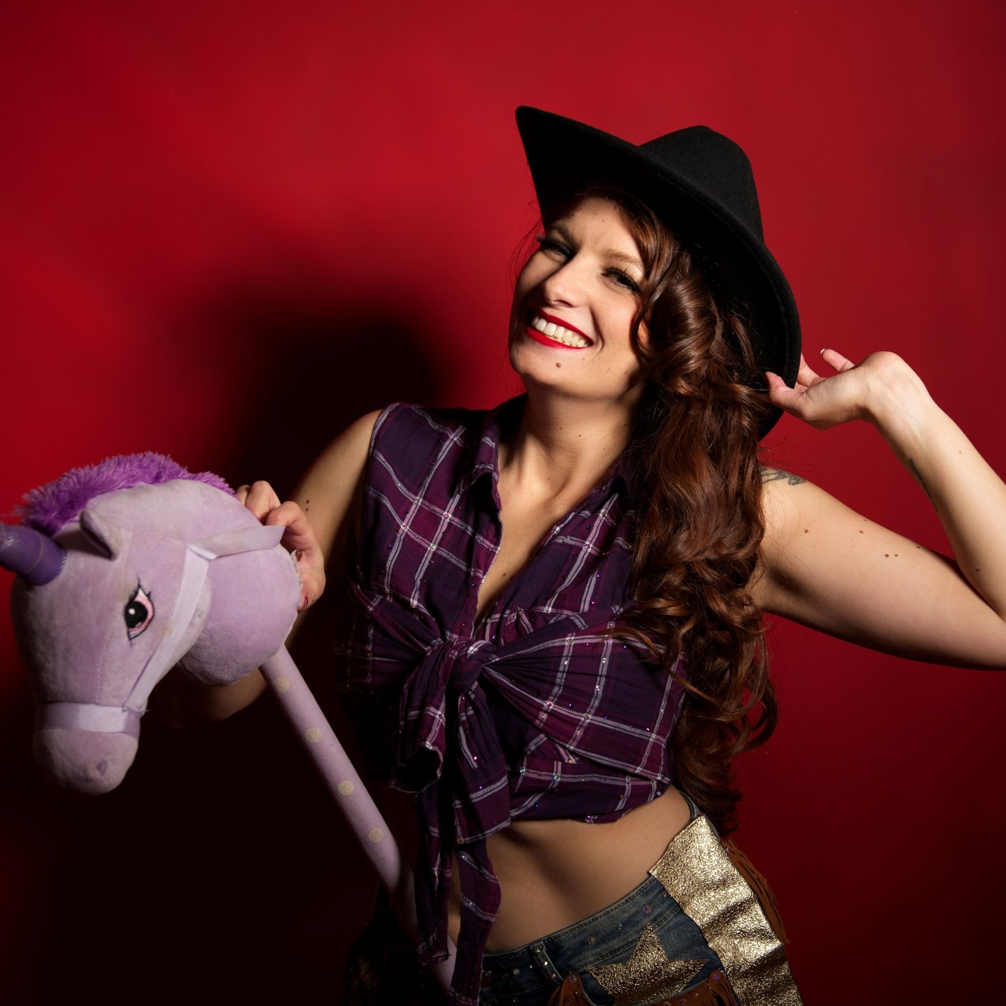 Pin up cowgirl avec chapeau et chemise à carreaux, sur un cheval en peluche