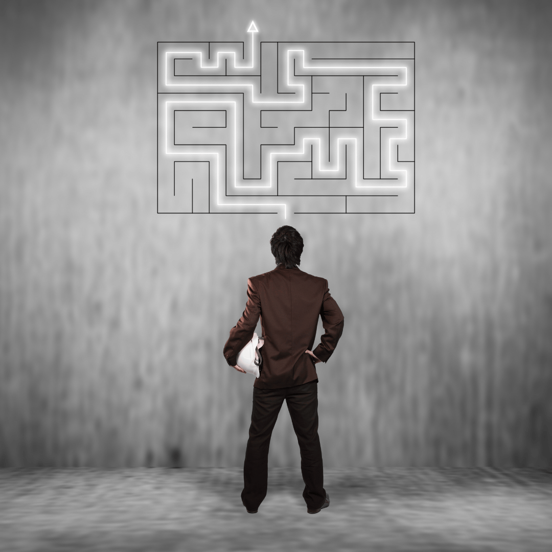 Um homem olha uma parede com um desenho de labirinto e faz um traçado para a saída.