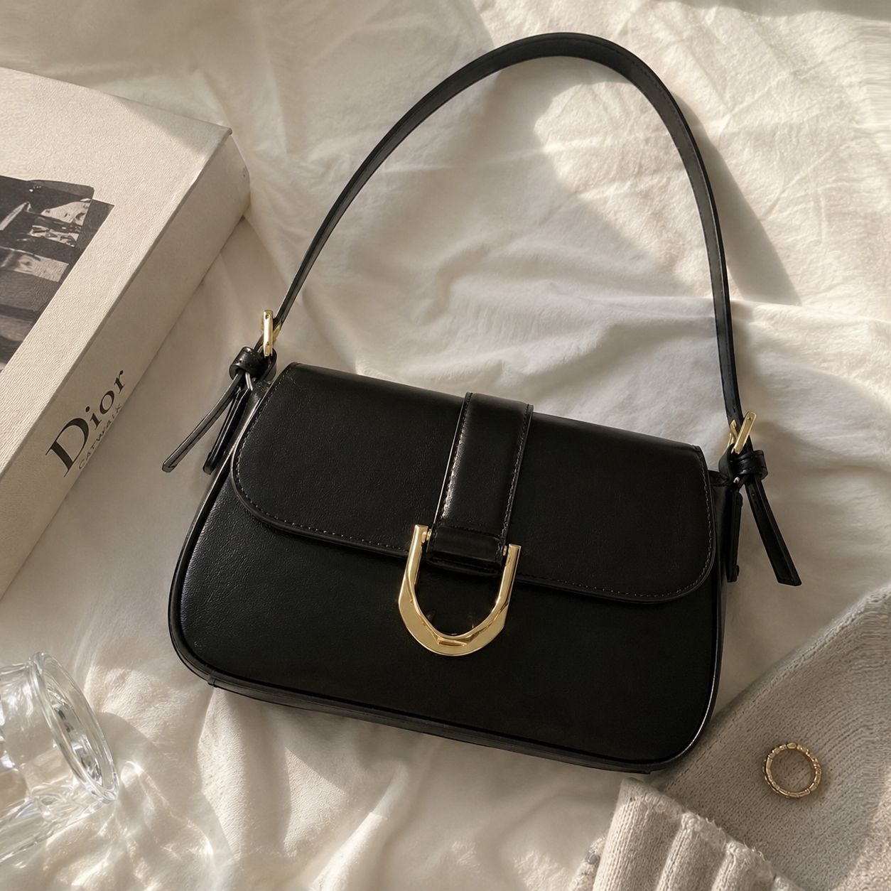 Woman wearing a black leather shoulder bag with gold buckle.