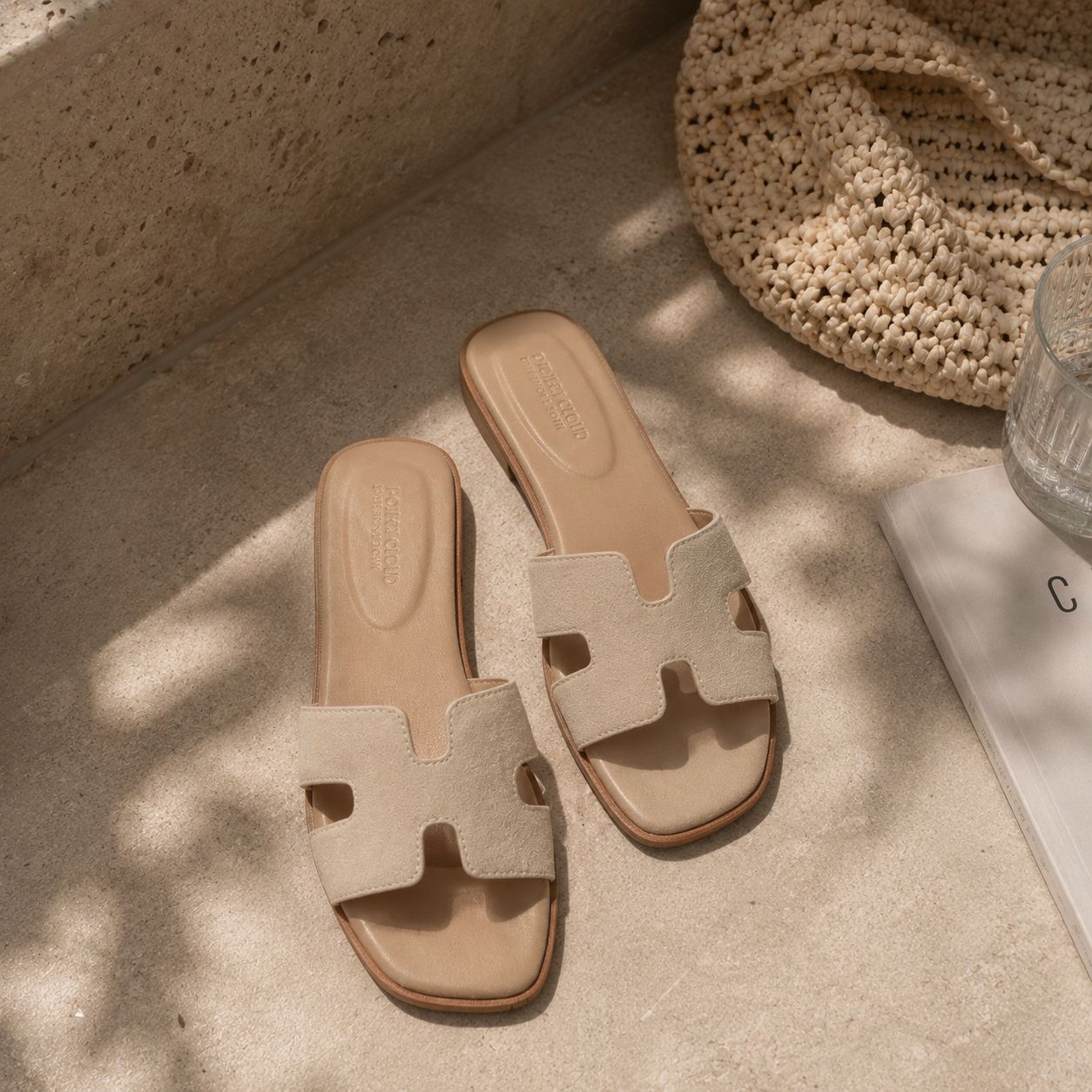 Beige suede slide sandals styled on a warm stone floor with soft sunlight and neutral summer vibe.