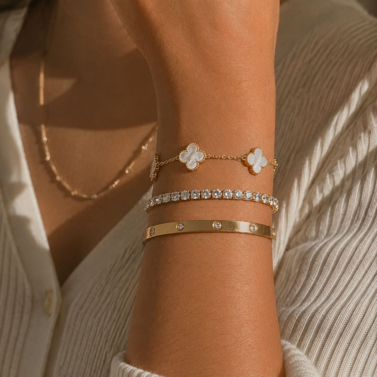 Three gold bracelets styled on a beige stone surface with soft natural lighting