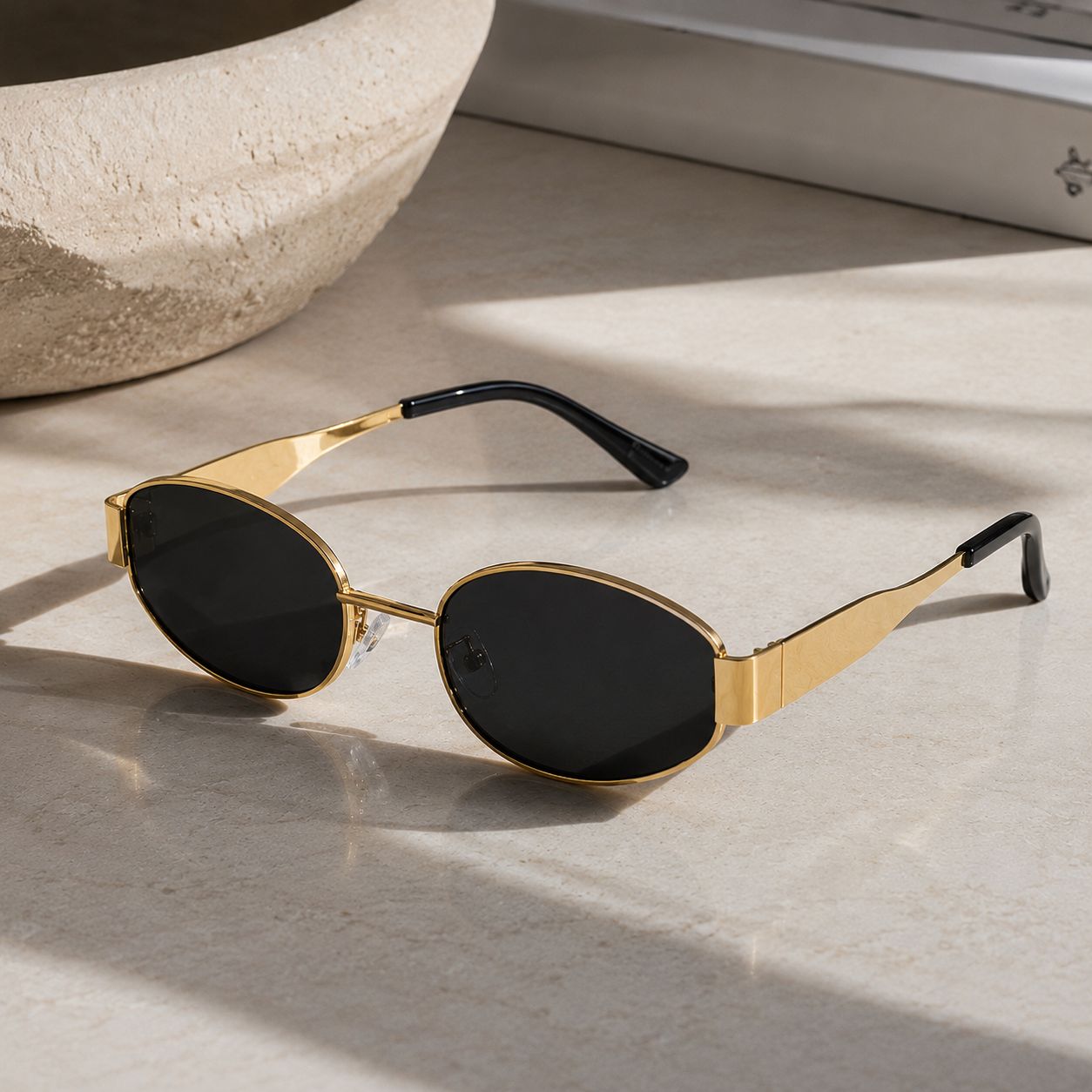 Gold oval sunglasses with black lenses on a clean background.