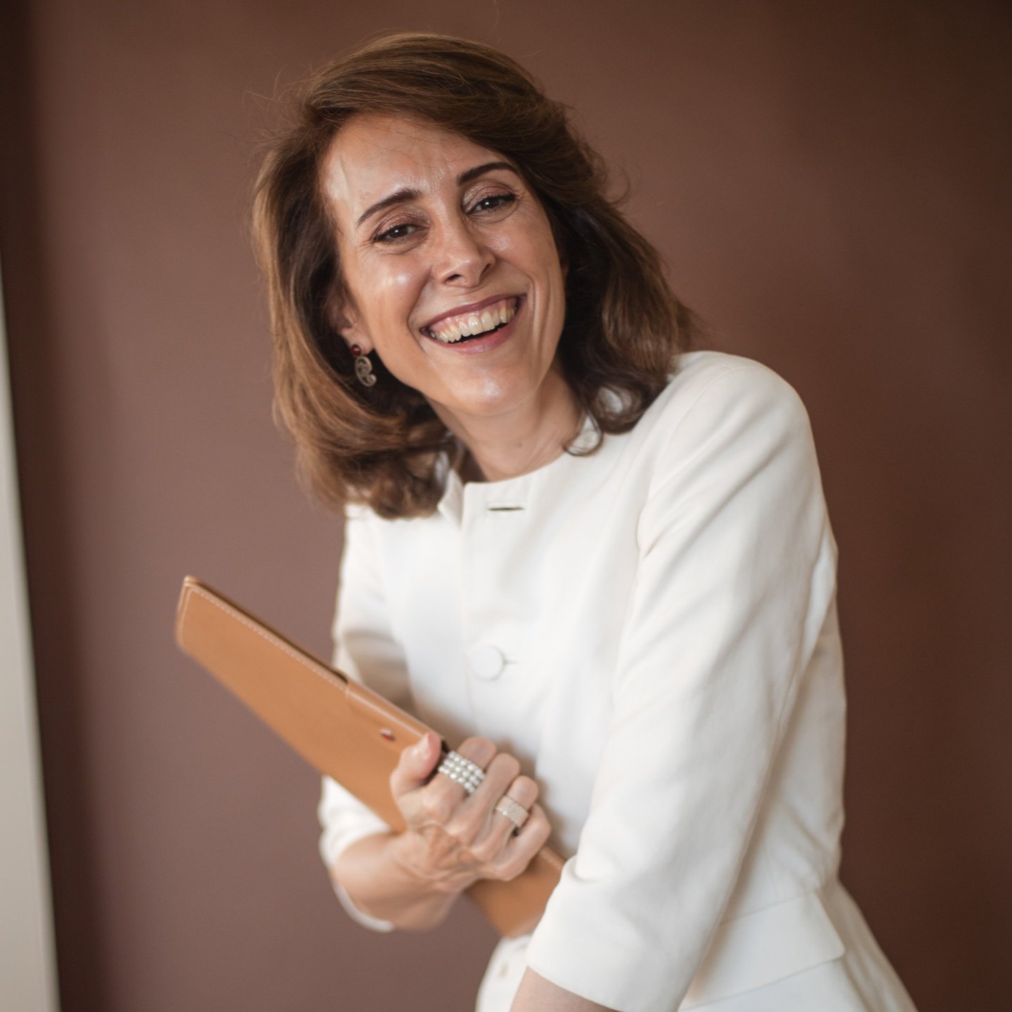 a female life coach in a white jacket holding a brown clutch