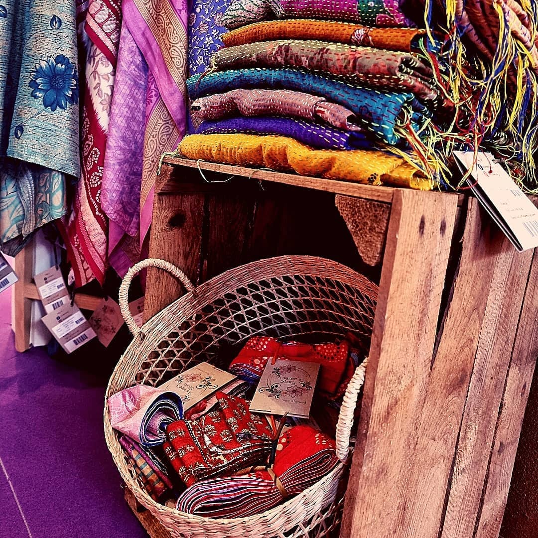 Folded vintage Indian sarees stacked in warm, earthy tones.