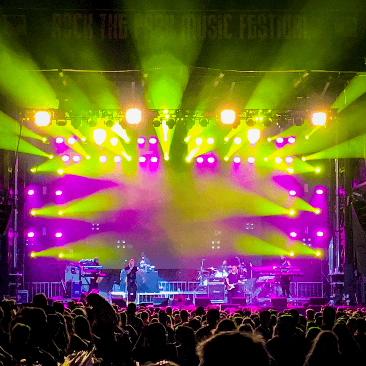 Lots of LED moving head fixtures on an outdoor stage at a music festival.