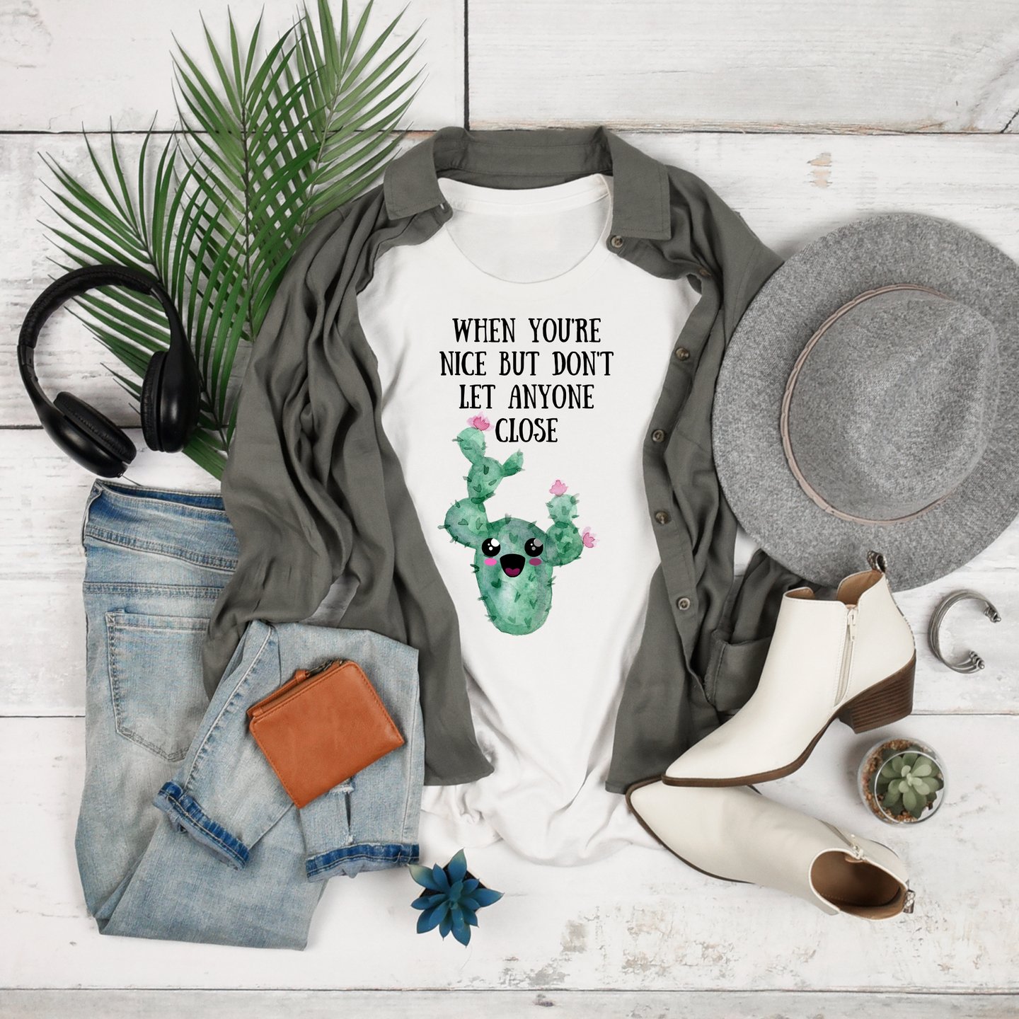 Plant-themed graphic tees and cozy hoodies displayed flatlay with jeans, boots, and greenery — Miss Chatty Plants apparel.