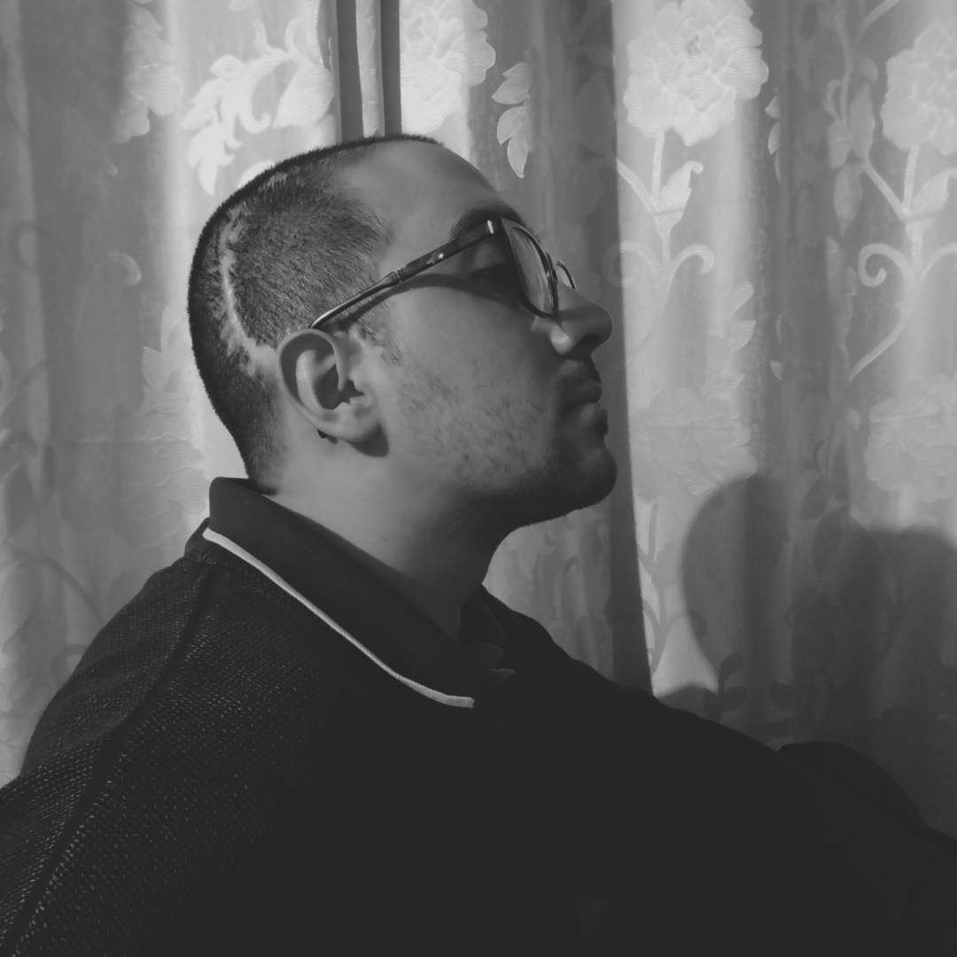 Perfil de hombre con larga cicatriz en el cerebro con gafas frente a una cortina en blanco y negro.