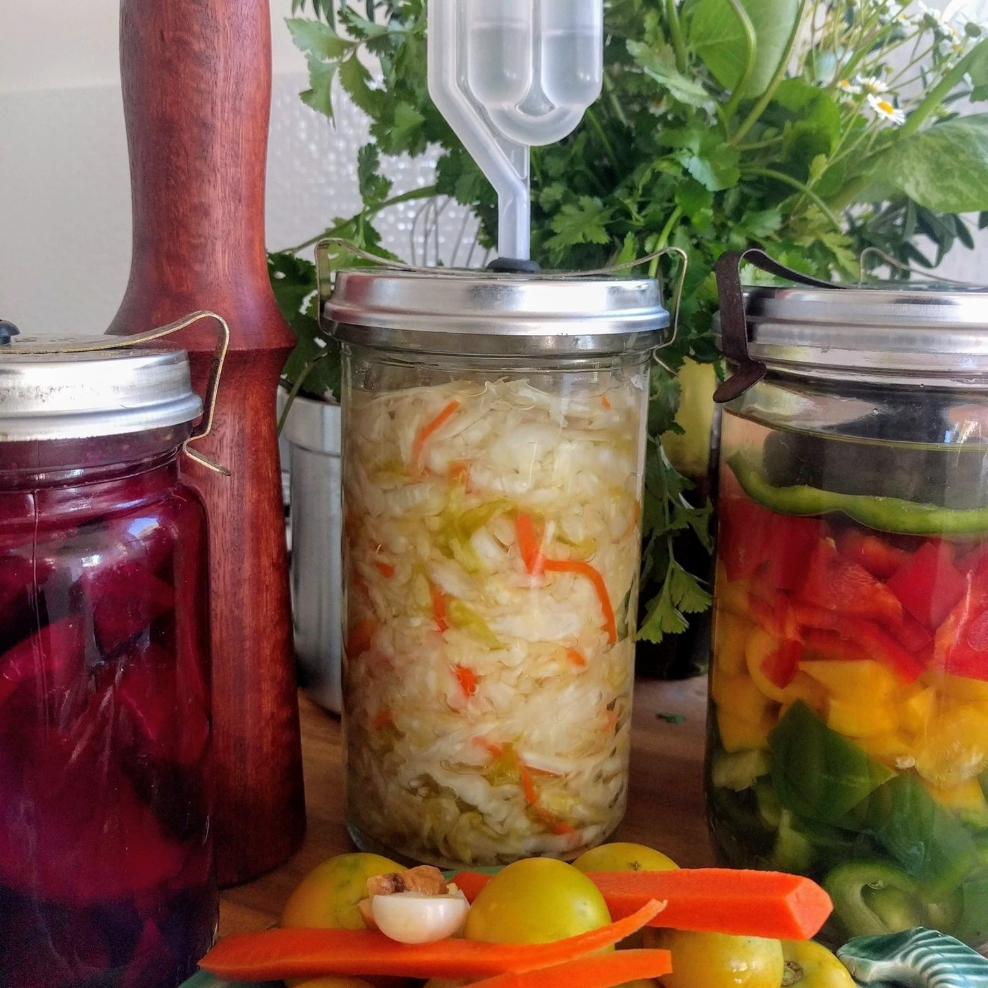 jars in colourful fermented food and wooden tamper