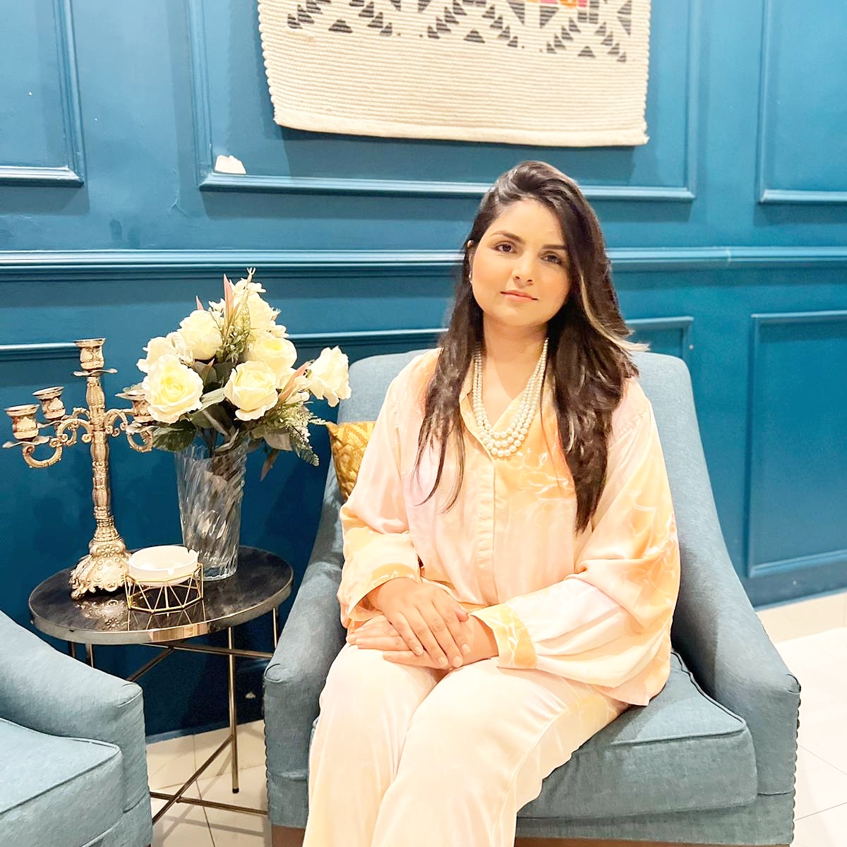 a woman sitting in a chair with a vase of flowers