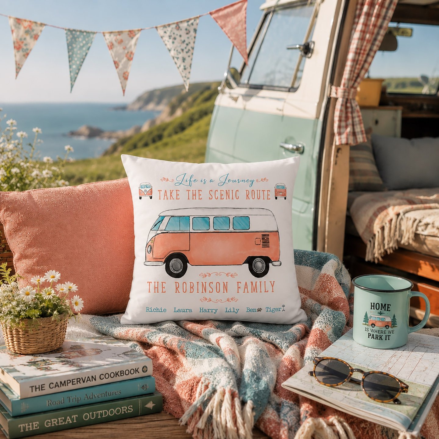 Personalised campervan family cushion displayed outside a vintage camper overlooking the coast. Pers