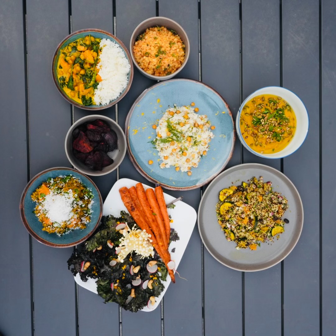 a table with bowls of vegetarian plant-based food and a bowl of vegetables carrots chickpeas