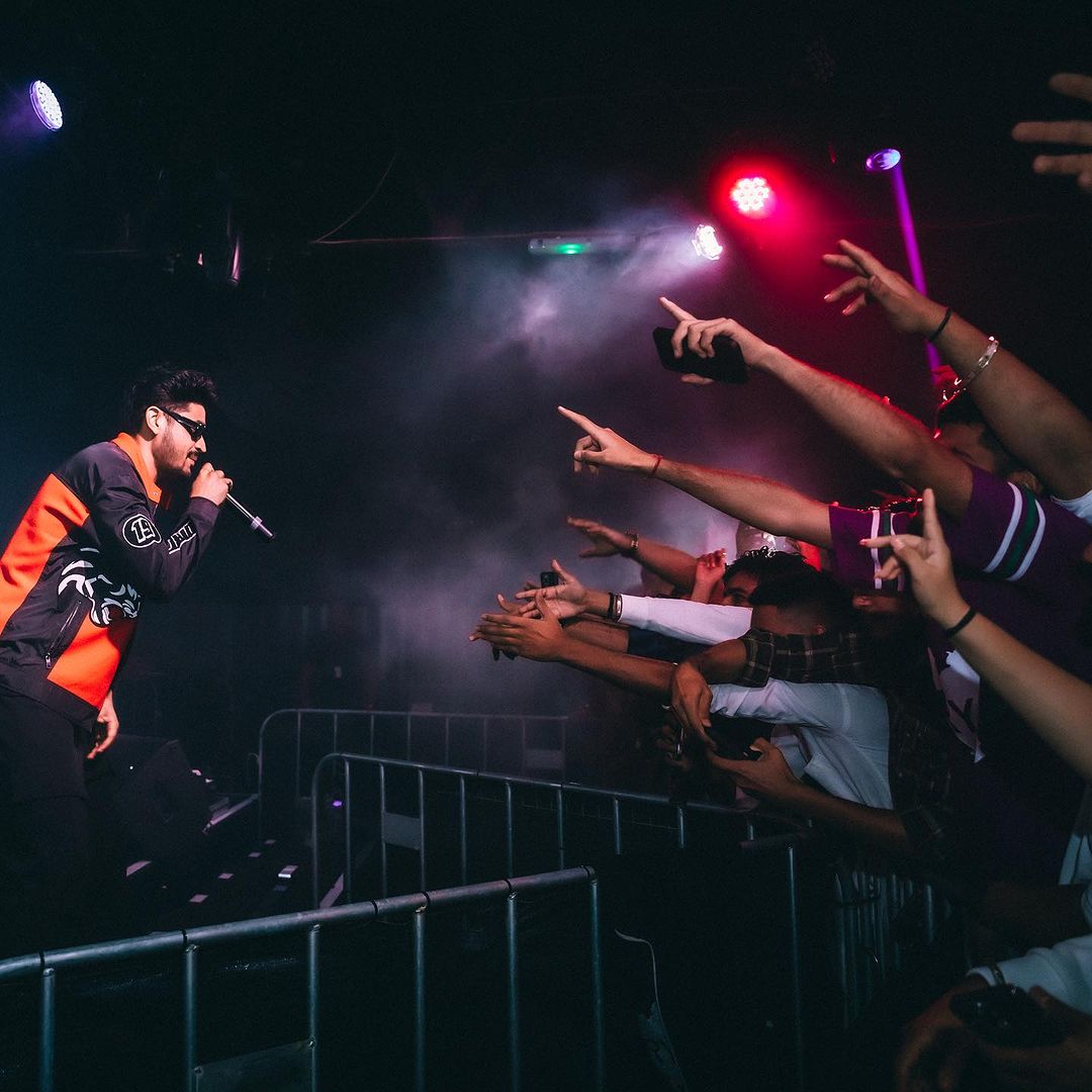 a man in a jacket and sunglasses on stage