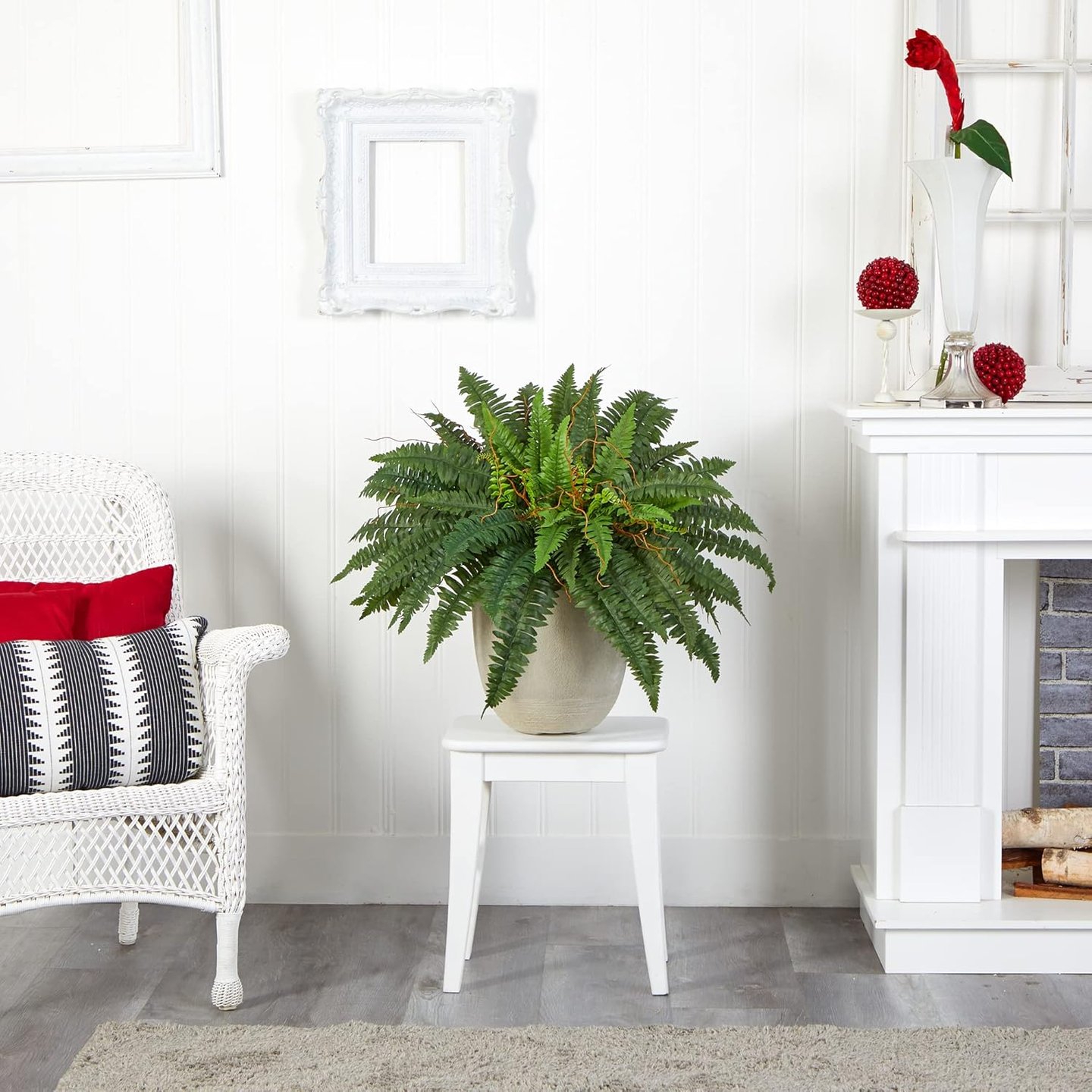 A lifelike artificial fern plant in a ceramic pot on a white stool, enhancing a cozy living room with a wicker chair and