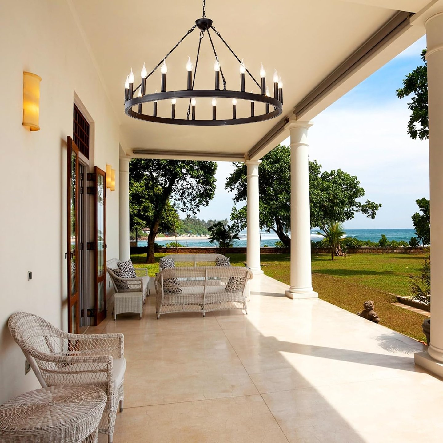 Modern black wagon wheel chandelier hanging over a luxury patio with ocean views.