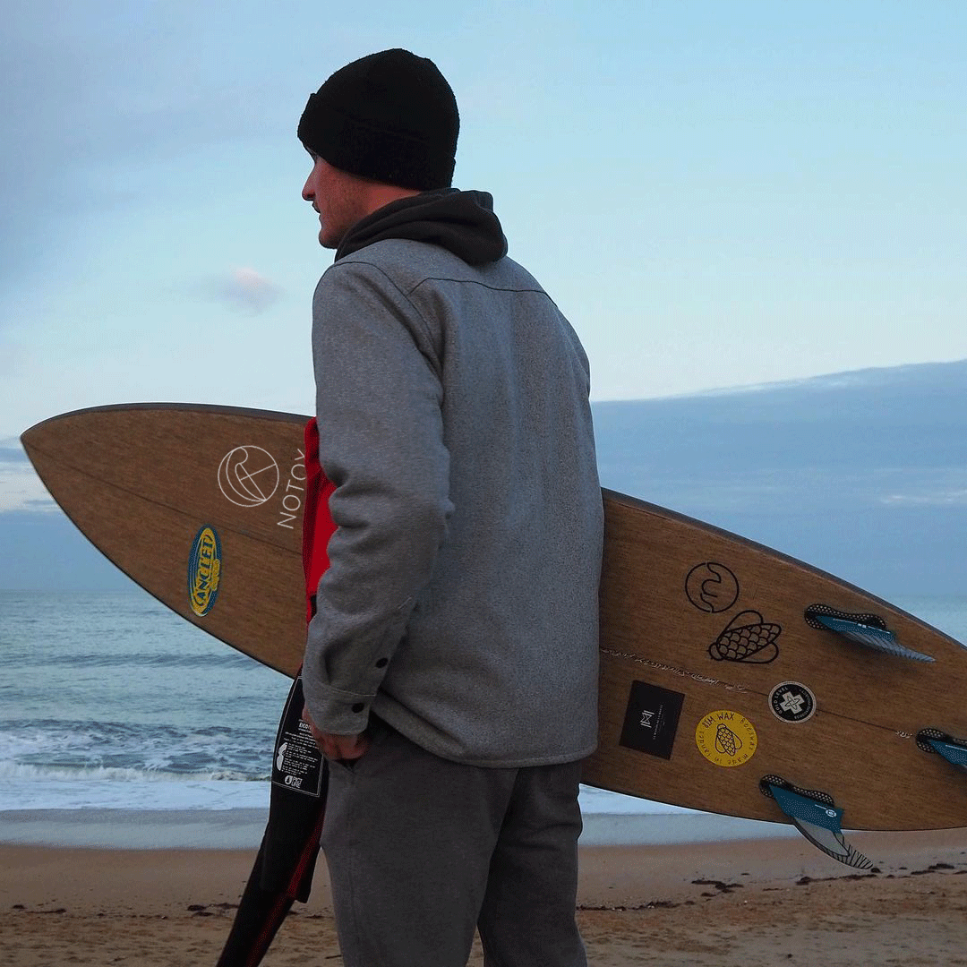 a man in a gray jacket and a surfboard