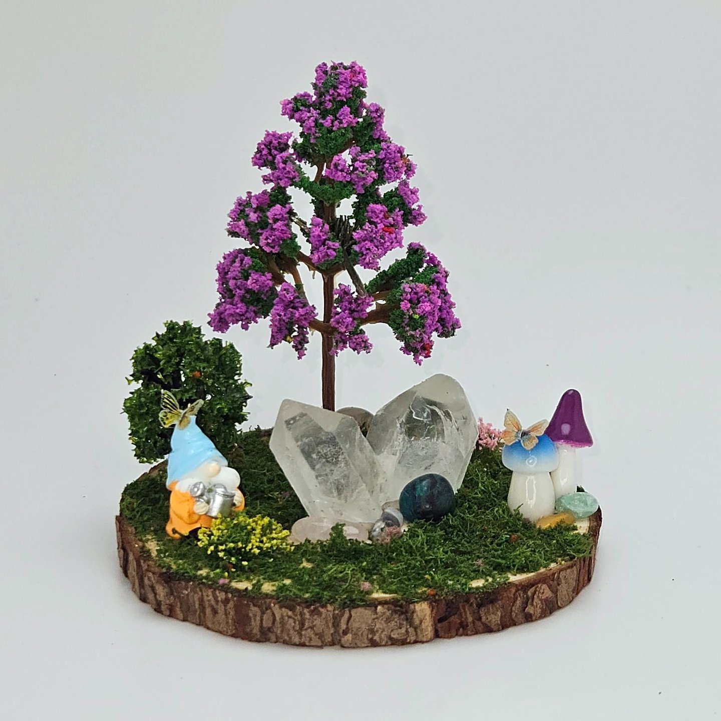 A decoration, a small circle of wood made to look like a gnome in a fairy forest with quartz crystal