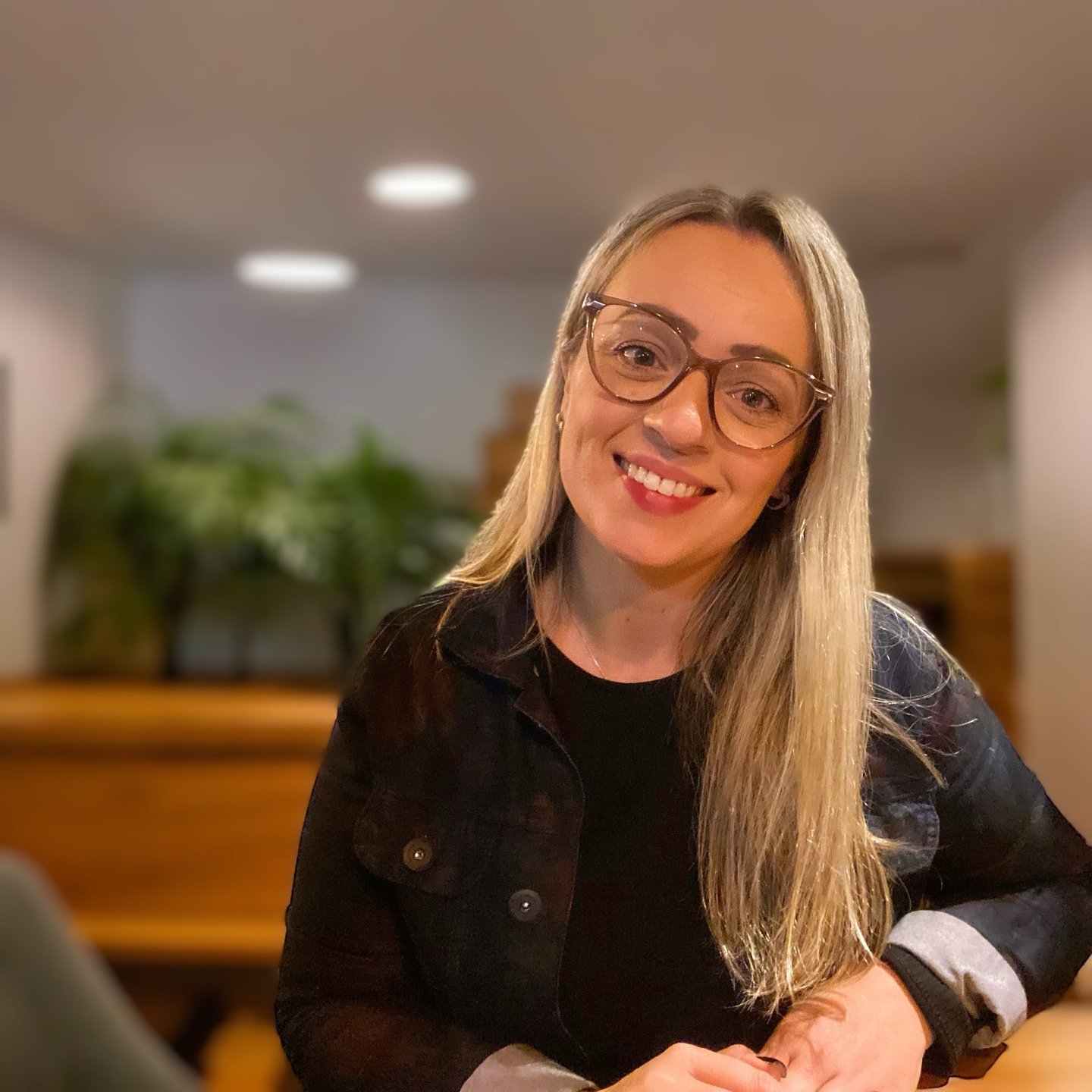 uma mulher de óculos e jaqueta preta sorrindo