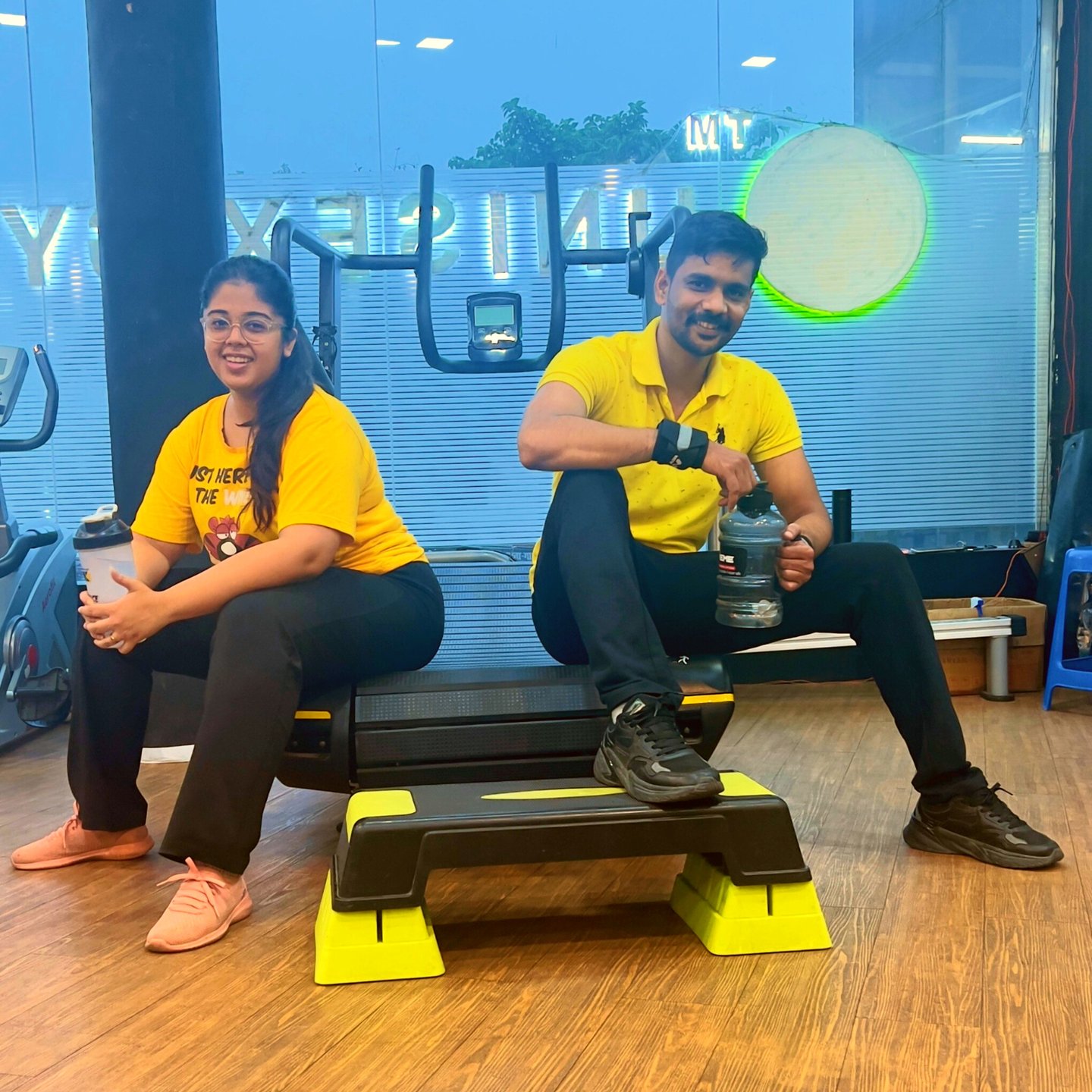 a man and woman sitting on a bench in a gym