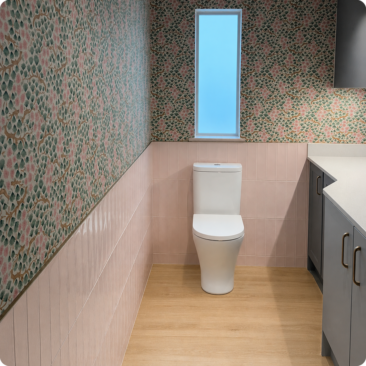 Modern bathroom featuring floral wallpaper, pink vertical tiles, and a white toilet in Brighton.