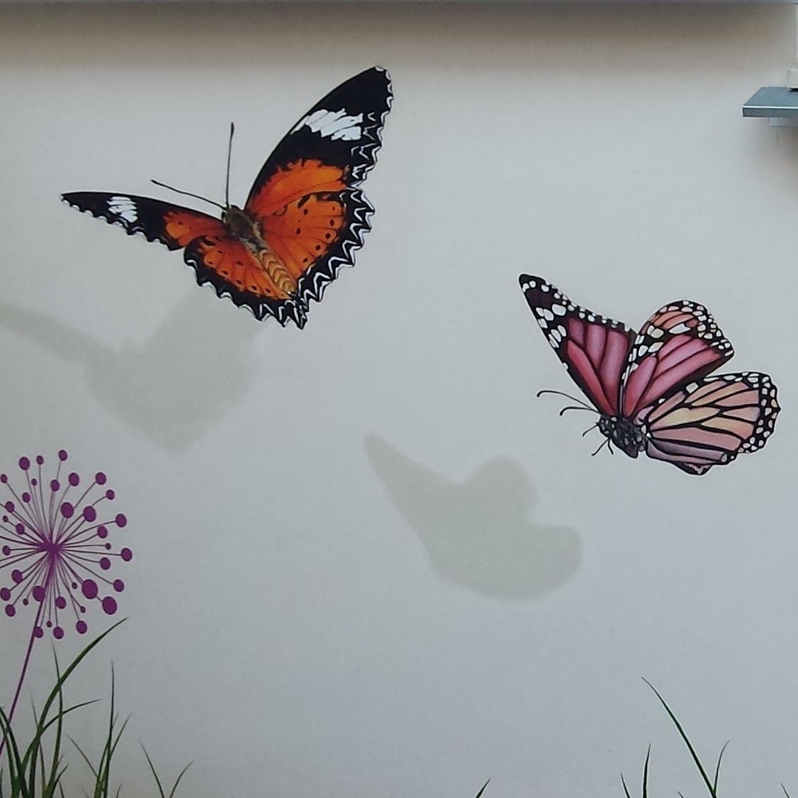 Détail d'une fresque murale extérieure: un beau papillon orangé vole. Lons-le-Saunier, Jura, 39.