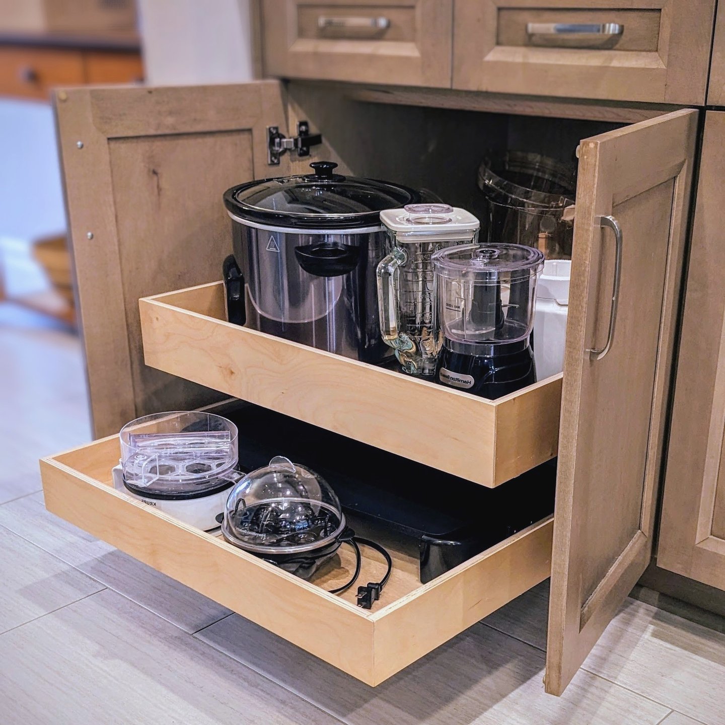 A cabinet drawer is extended out from the cabinet showing heavy kitchen appliances.