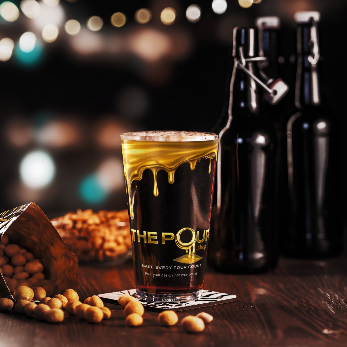 The Pour Shop branded pint glass on table with beer and bottles showing hospitality drinkware in bar style setting
