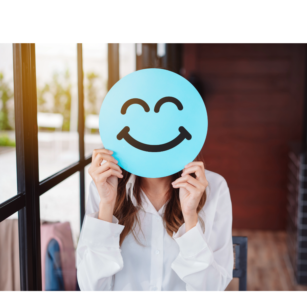 Girl covering her face with an image of a emoticon smiley face
