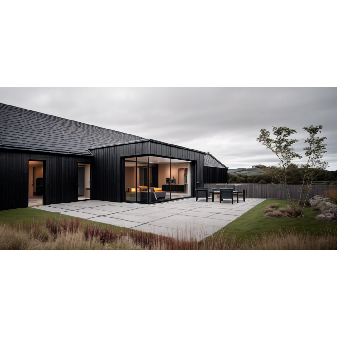 Modern black timber house with a glass-walled living room and paved outdoor patio at dusk.