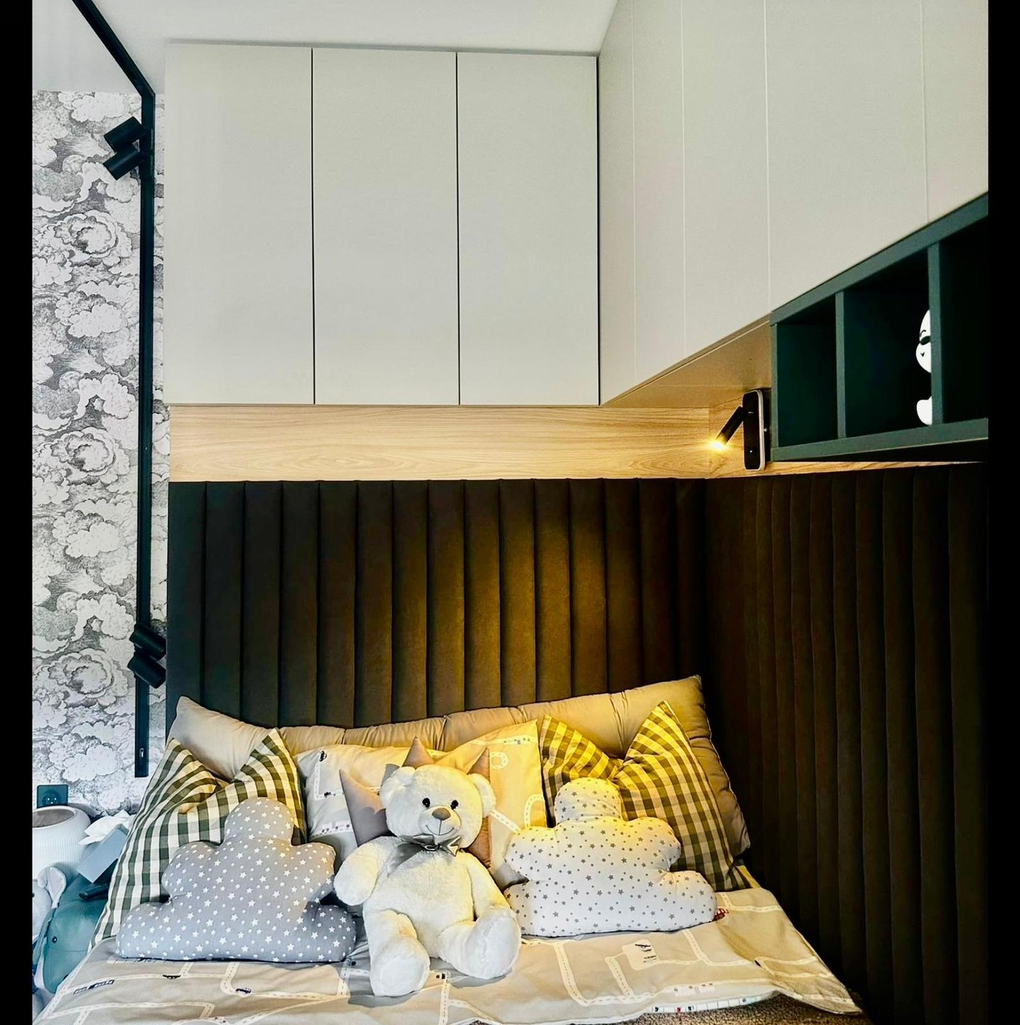 Modern kids bedroom with a built-in bed, black fluted headboard, white storage cabinets, and plush teddy bear toys.