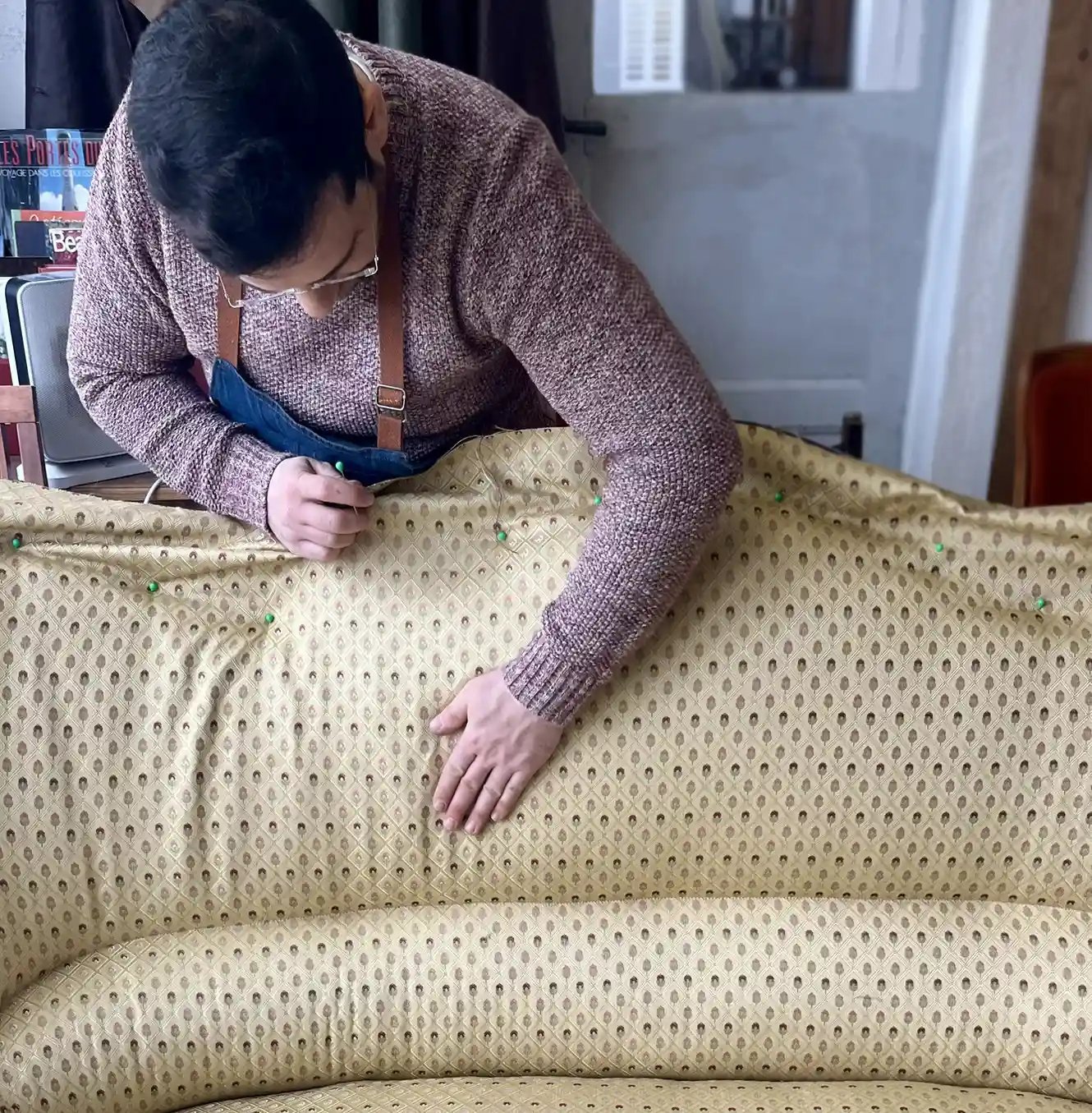 Un artisan couvre d'un tissu jaune à motifs un canapé