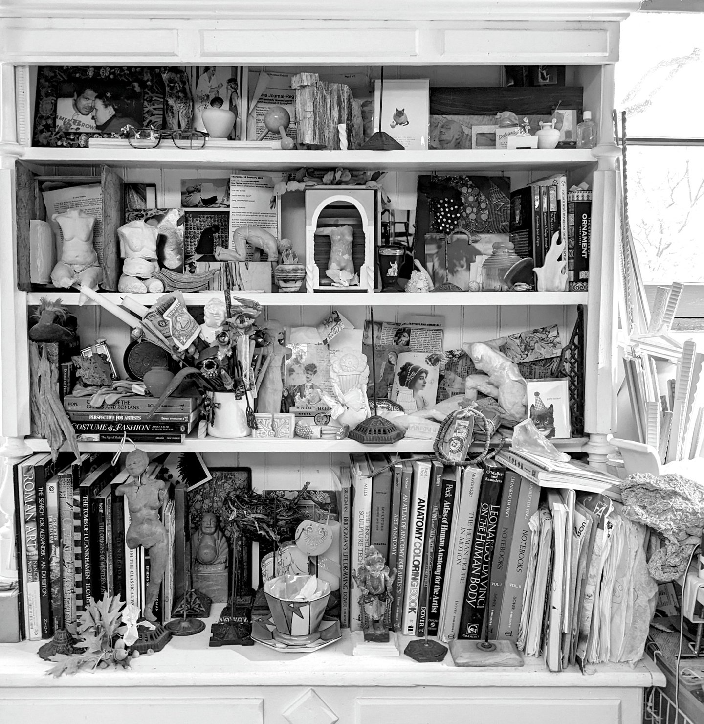 Bookshelves in the studio of Clea Carlsen filled with parts, pieces, found objects and other items collected by the artist.