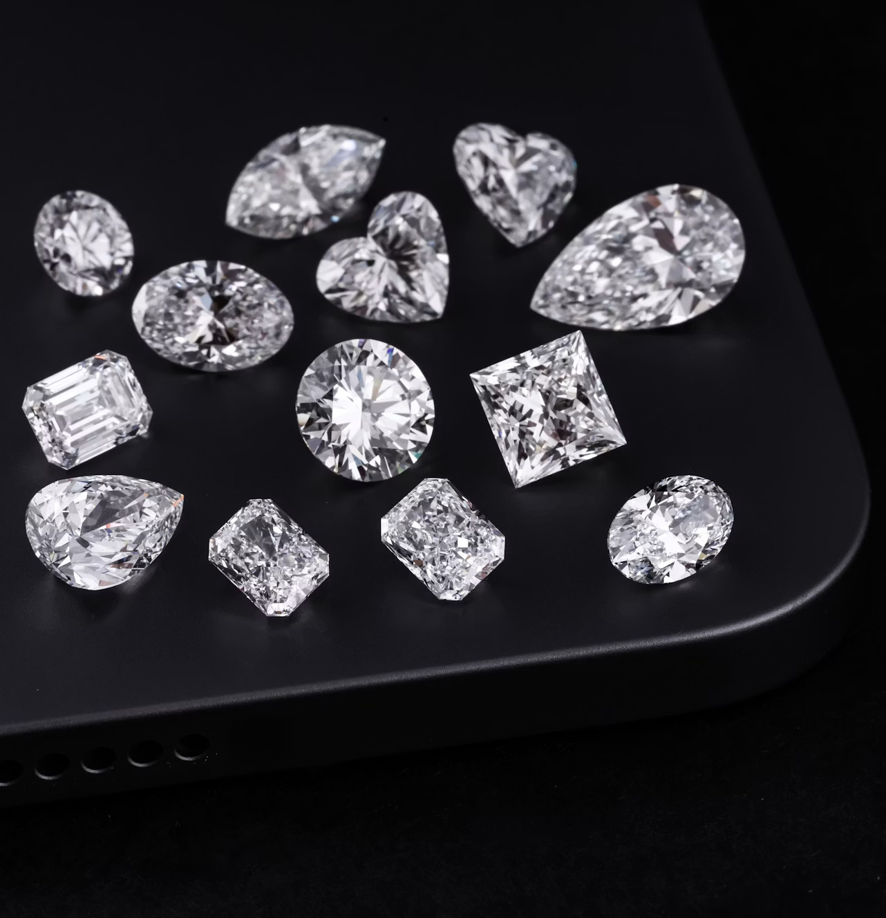 Diamonds of various shapes are on a black surface.