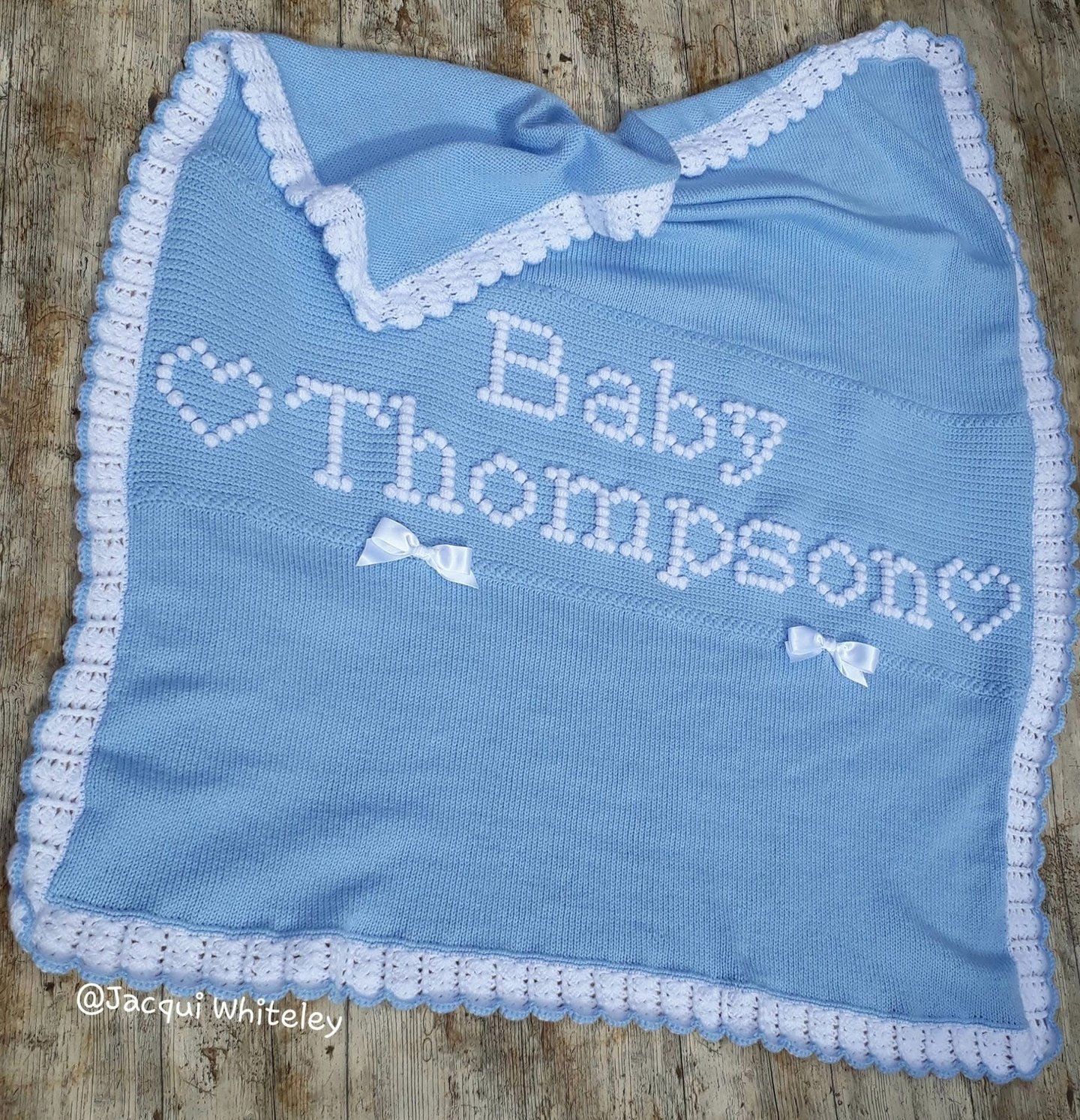 Custom made knitted and crochet baby blanket with raised lettering "Baby Thompson" and hearts.