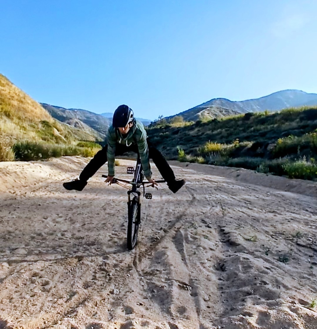 Mark Hower in a controlled bail going over the handlebars on a mountain bike on a sandy Southern Cal