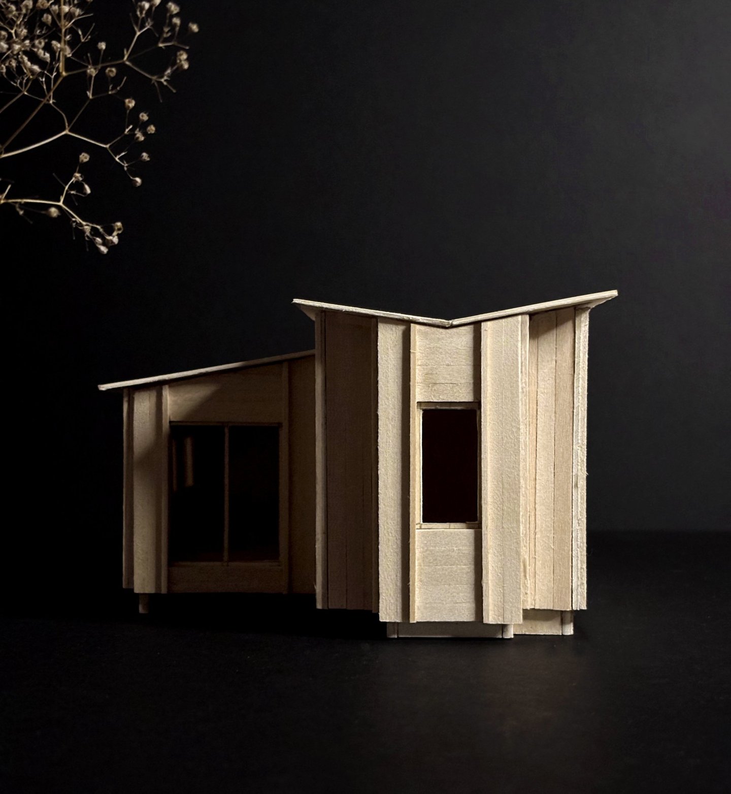 Handcrafted basswood architectural model of a modern cabin design against a dark background.
