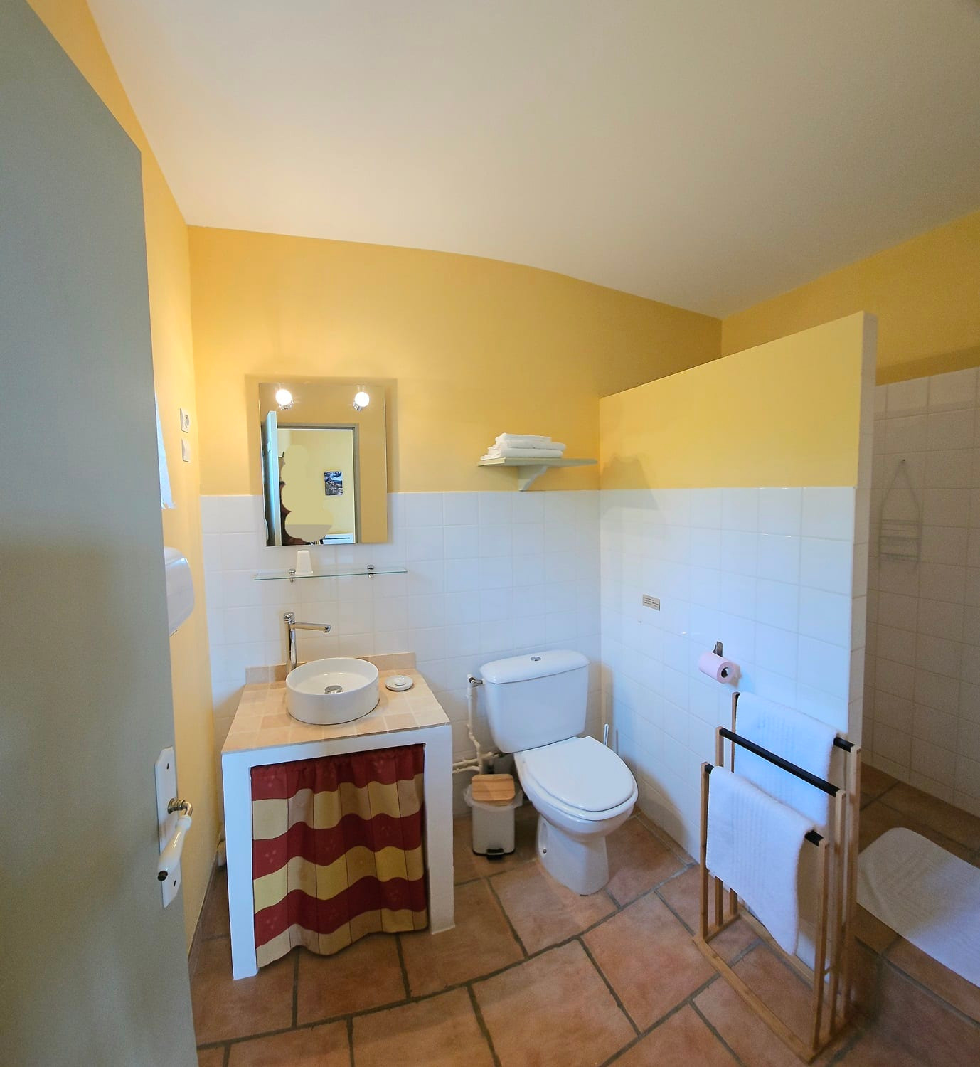 Salle de bain chambre ocre avec douche à l'italienne, wc, vasque et miroir.