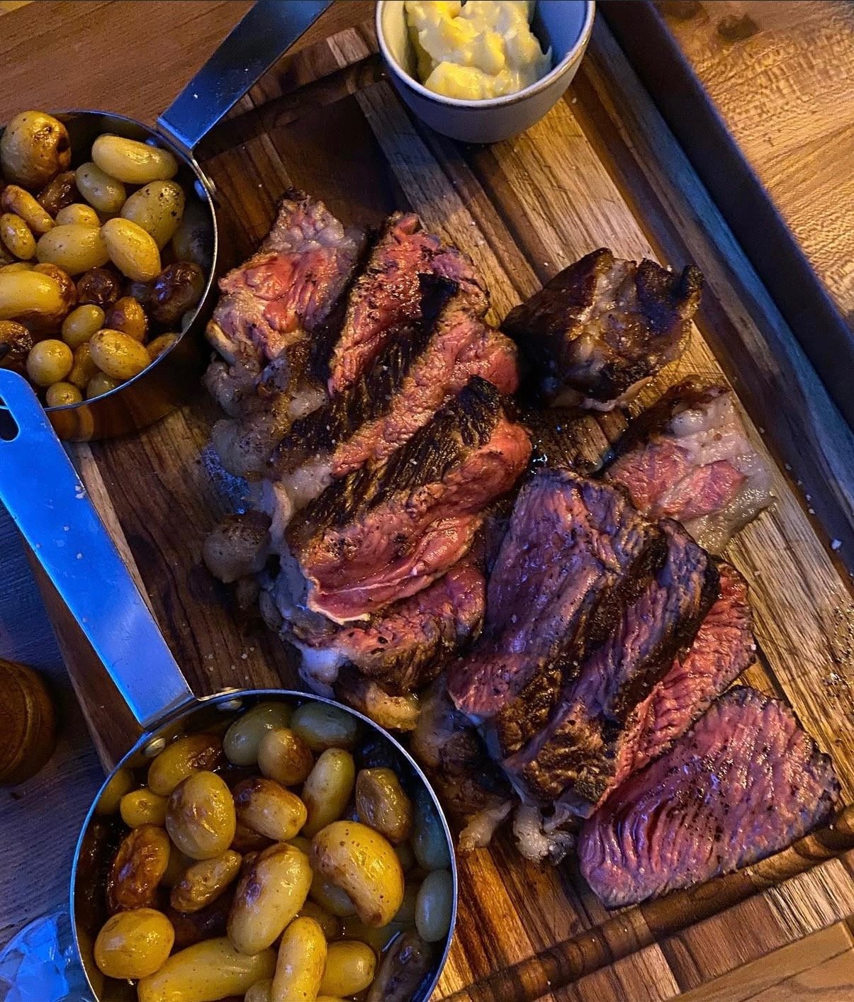 Une côte de bœuf découpée, accompagnée de pommes de terre grenaille.